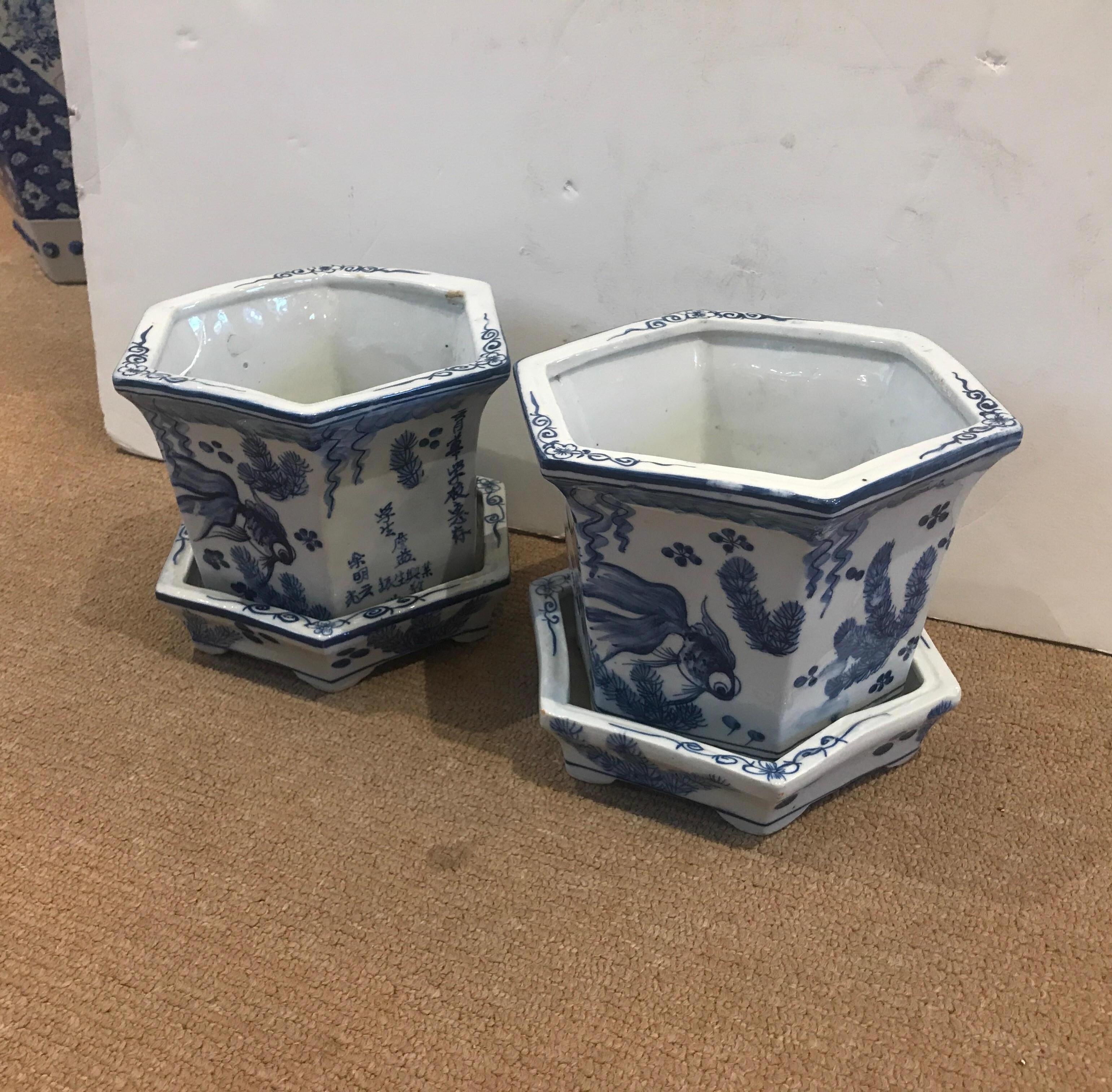 A pair of antique Chinese blue and white hand painted porcelain cachepot planters with underplates. The white porcelain background with blue decoration of Koi fish.