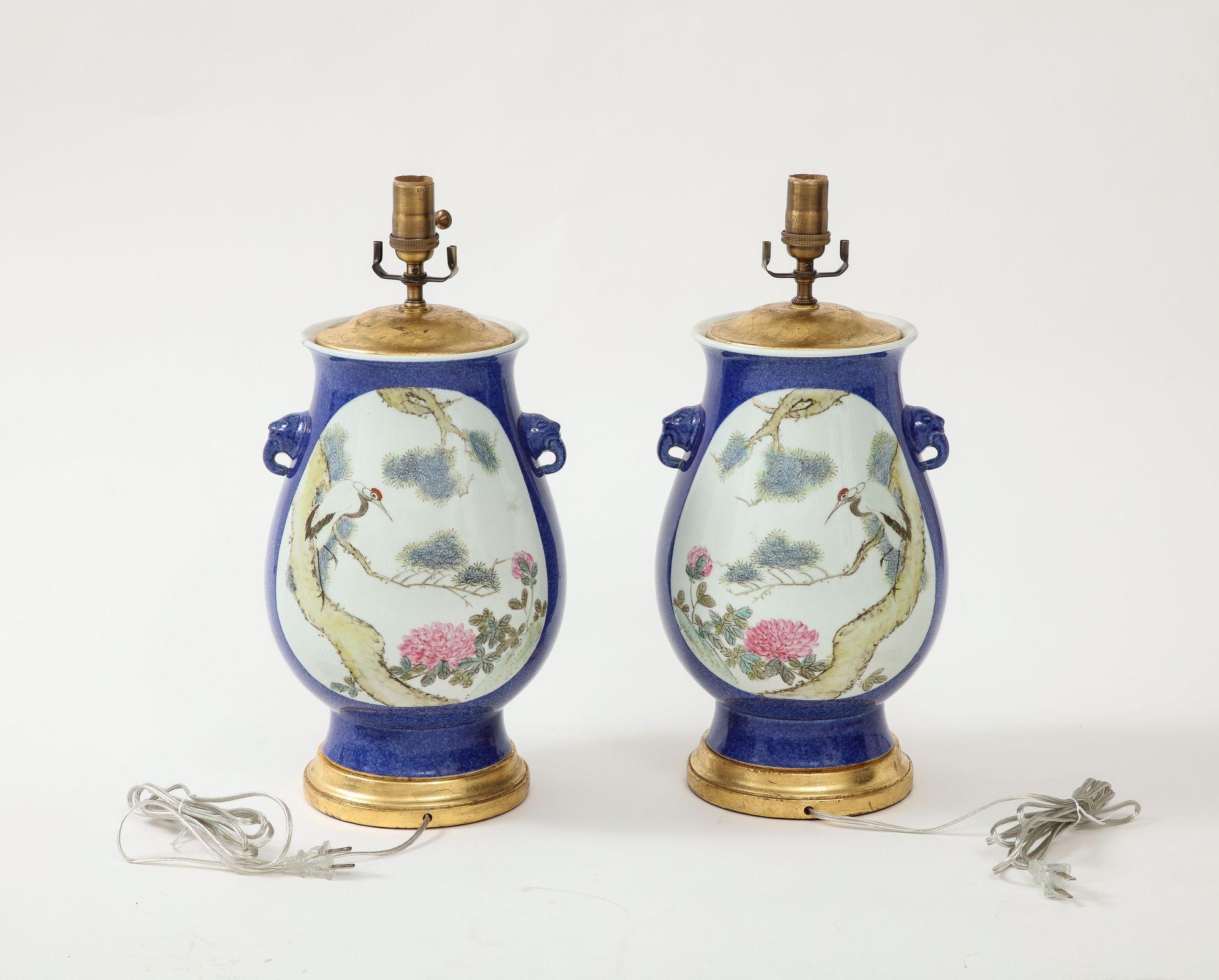 These lamps are special for their stunning color. The urn-shaped body of the lamps is a bright, beautiful blue glaze, with a center medallion decorated with a scenic scene of flowers and birds in soft pastel colors. The giltwood base finishes the