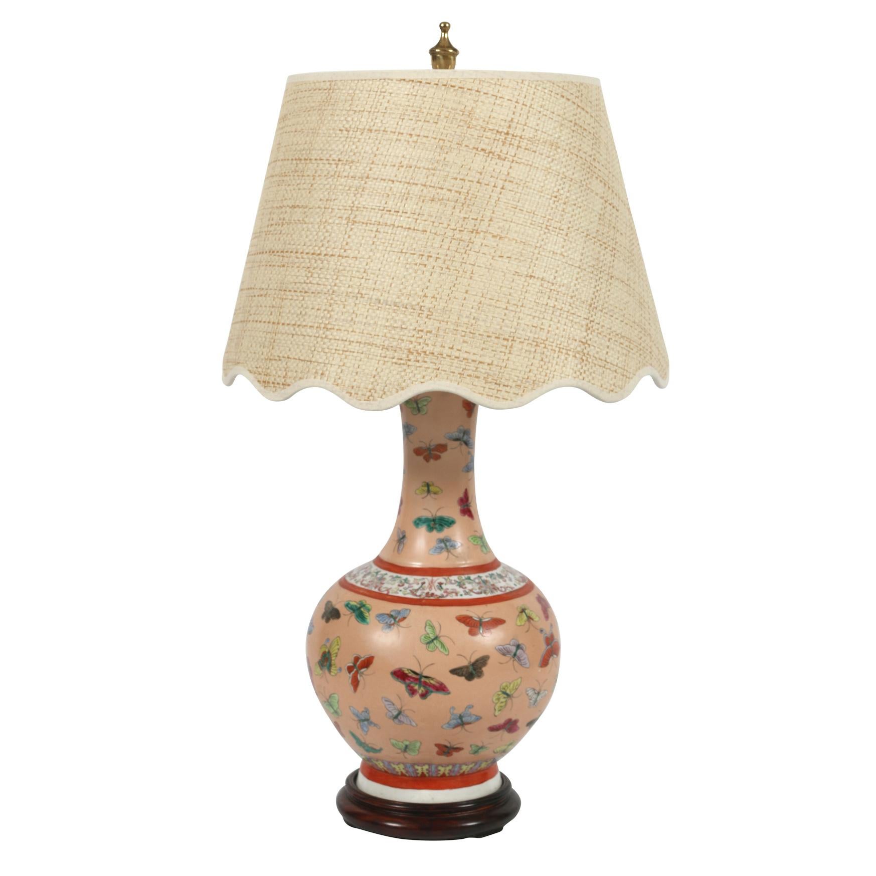 Pair of Chinese porcelain lamps with colorful butterflies on a pink background.