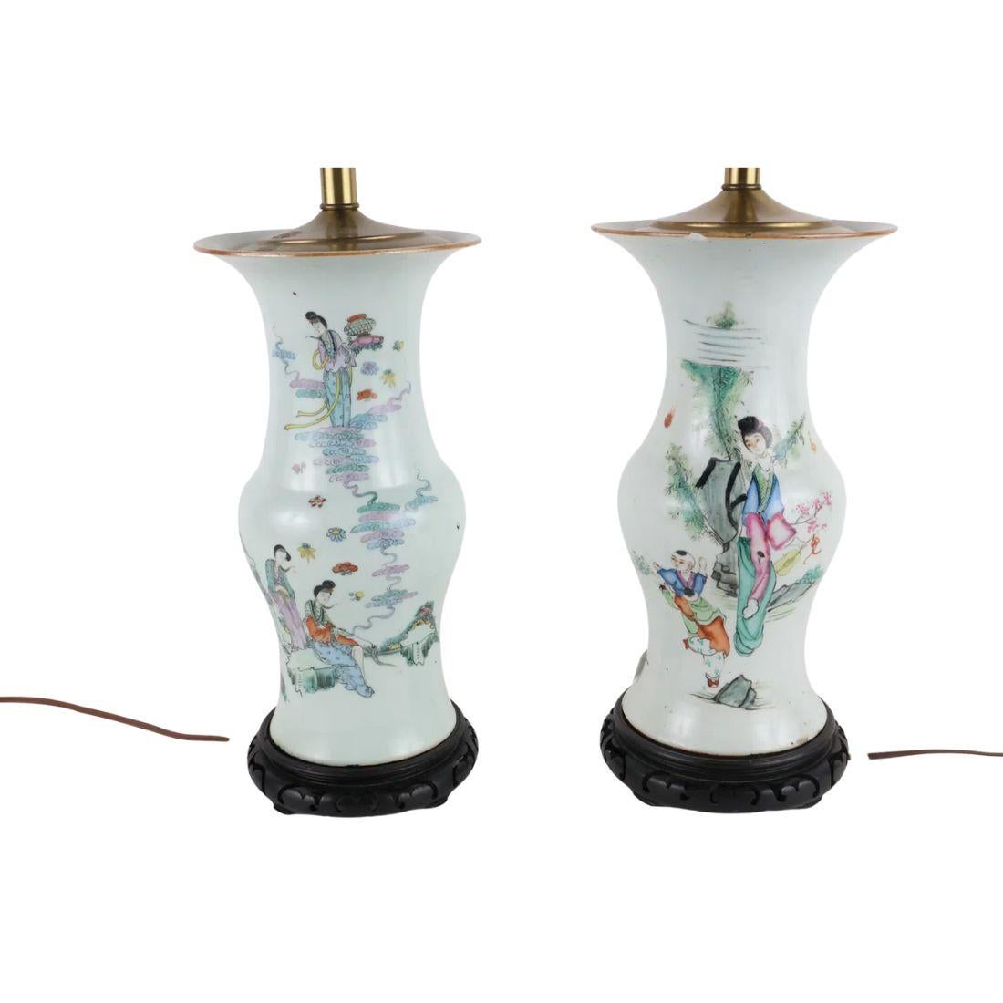 Dieses auffällige und elegante Paar chinesischer Porzellanlampen hat die klassische Form einer Vase mit komplizierten, farbenfrohen Figurenszenen auf einem strahlend weißen Keramikhintergrund. Jede Lampe steht auf einem fein geschnitzten Sockel aus