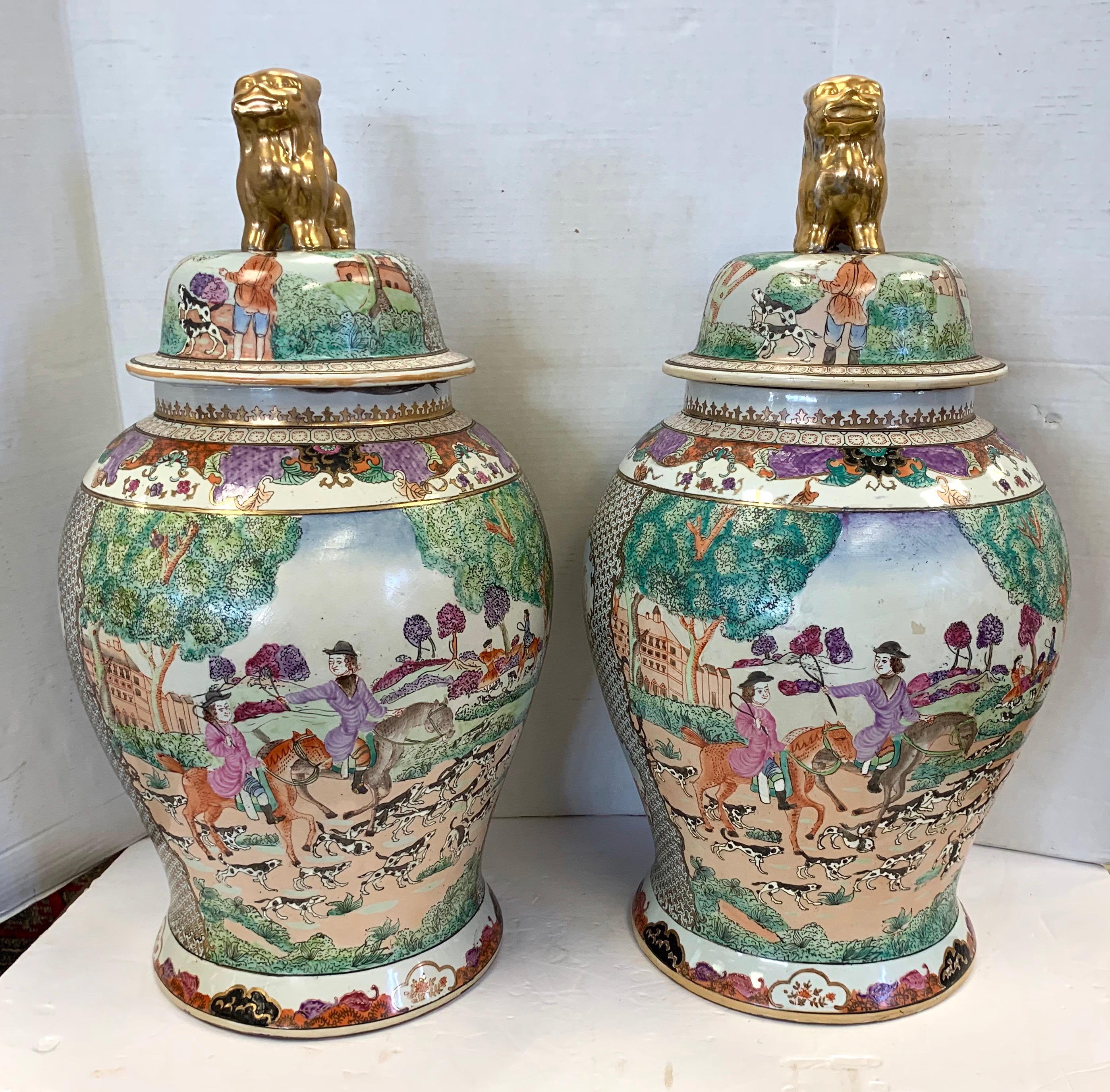 Magnificent large pair of matching vintage Chinese porcelain urns. What sets this pair apart is the art work which features English hunt scenes. They are topped with a gold foo dog. Please peruse all pictures, they are exquisite. Signed on bottom.