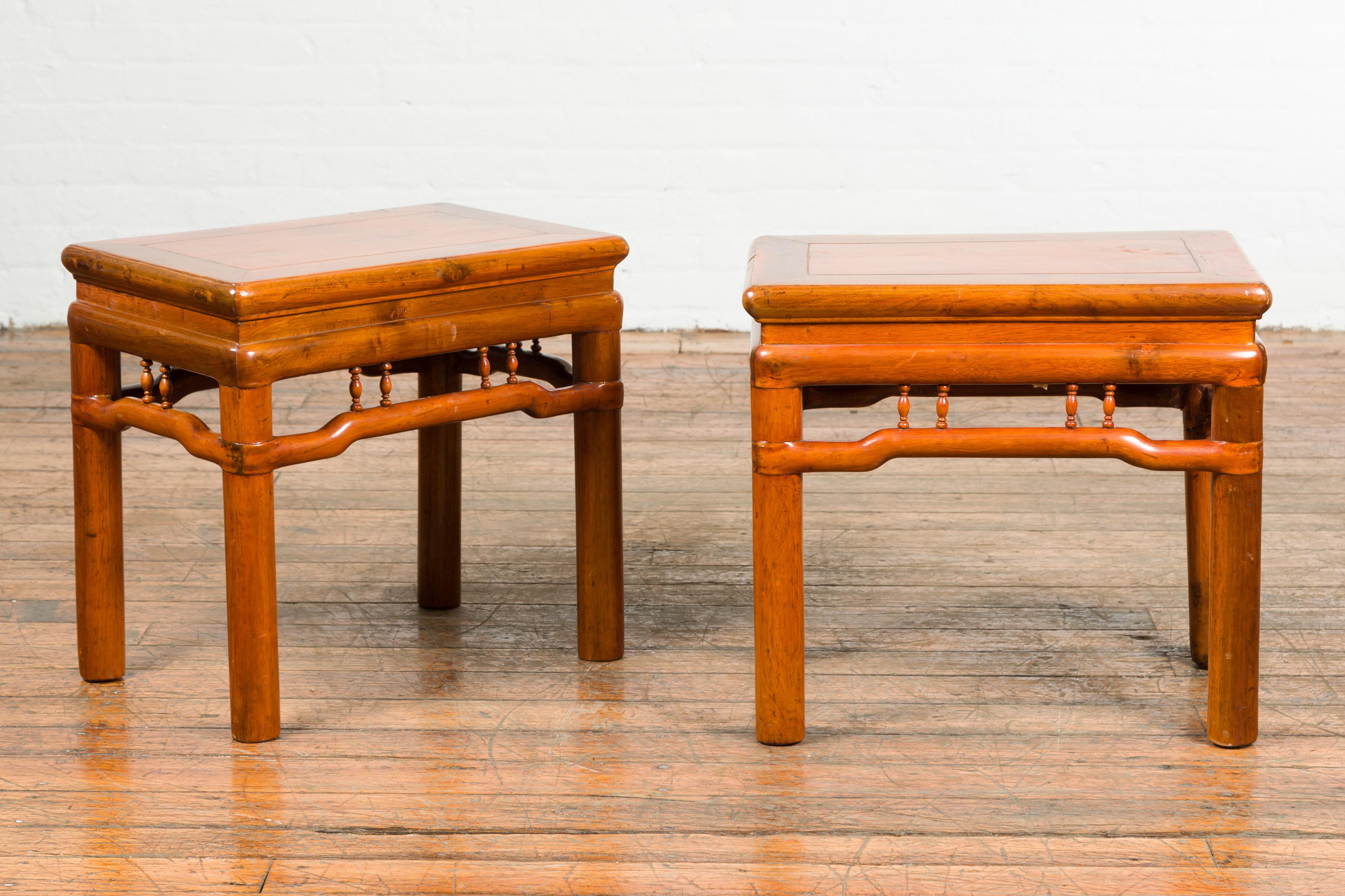 A pair of Chinese Qing Dynasty period side tables from the 19th century, with humpback stretchers. Created in China during the Qing Dynasty period, each of this pair of side tables features a square waisted top with central board, sitting above a