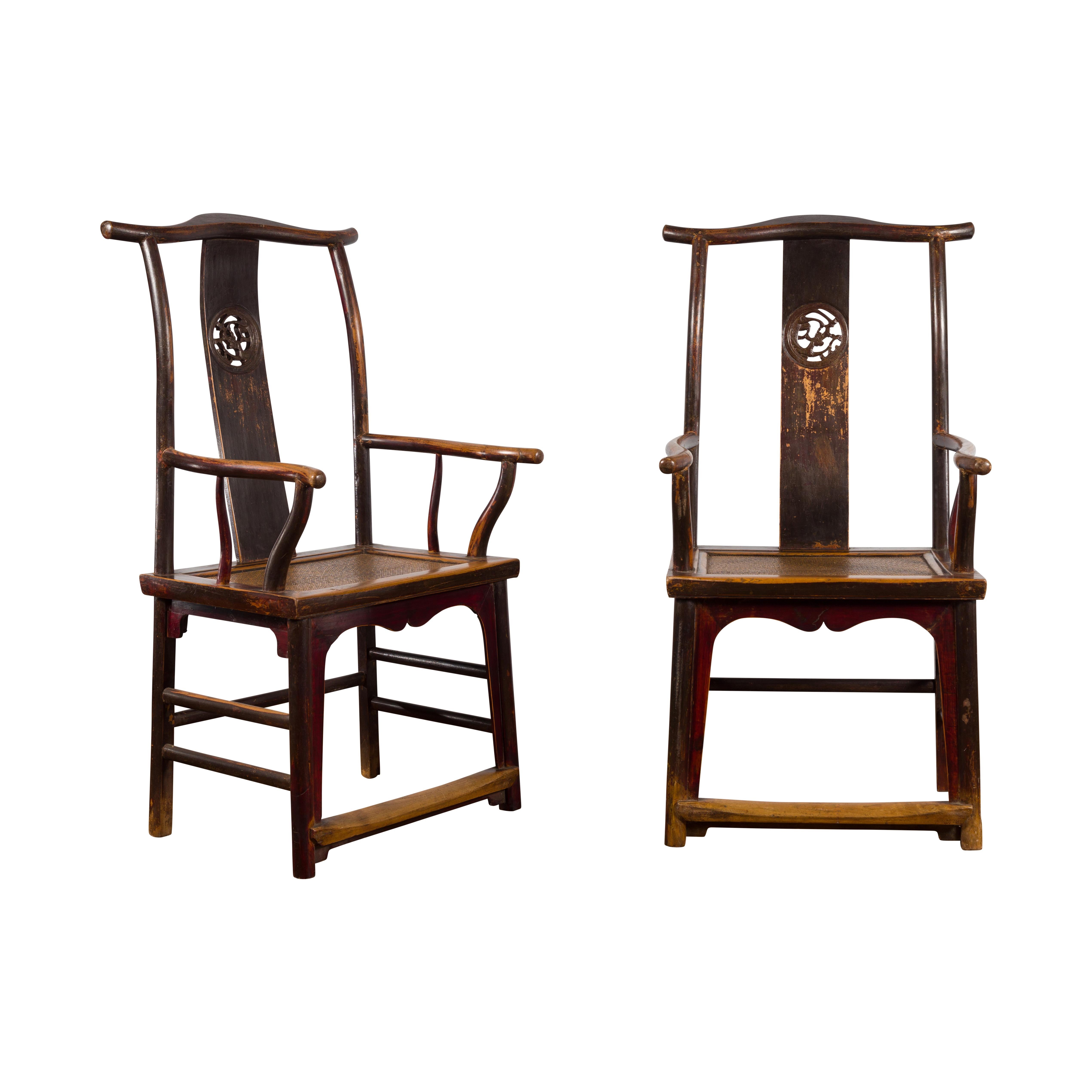 A pair of Chinese Qing Dynasty period yoke-back chairs from the 19th century, made from natural wood with carved splats. Created in China during the Qing Dynasty, each of this pair of armchairs features a tall back, topped with a curving rail. The