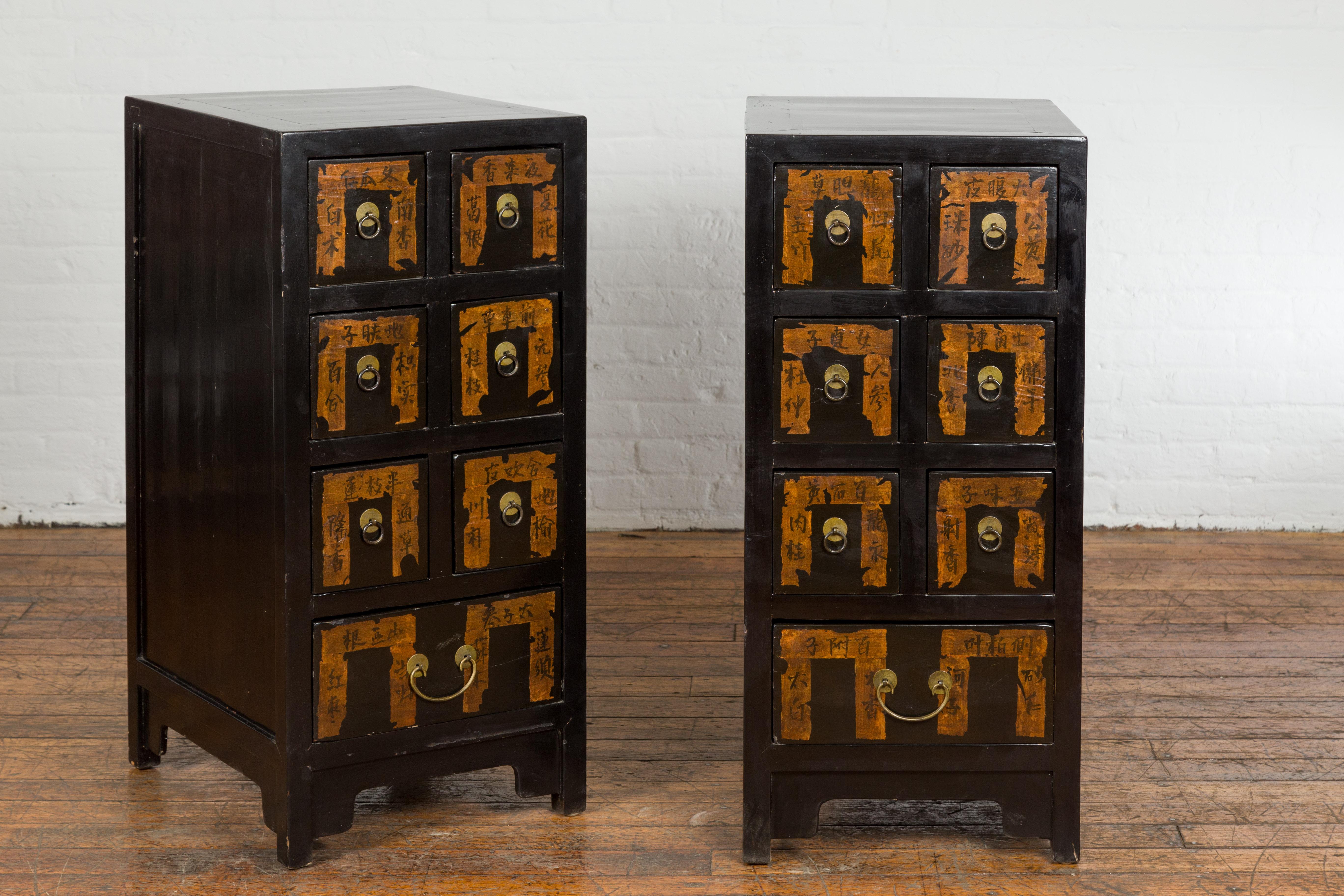 A pair of Chinese Qing Dynasty period black lacquer apothecary cabinets from the 19th century with seven drawers each, labels hand painted with calligraphy, brass hardware and carved aprons on straight legs. Embrace the timeless elegance and rich