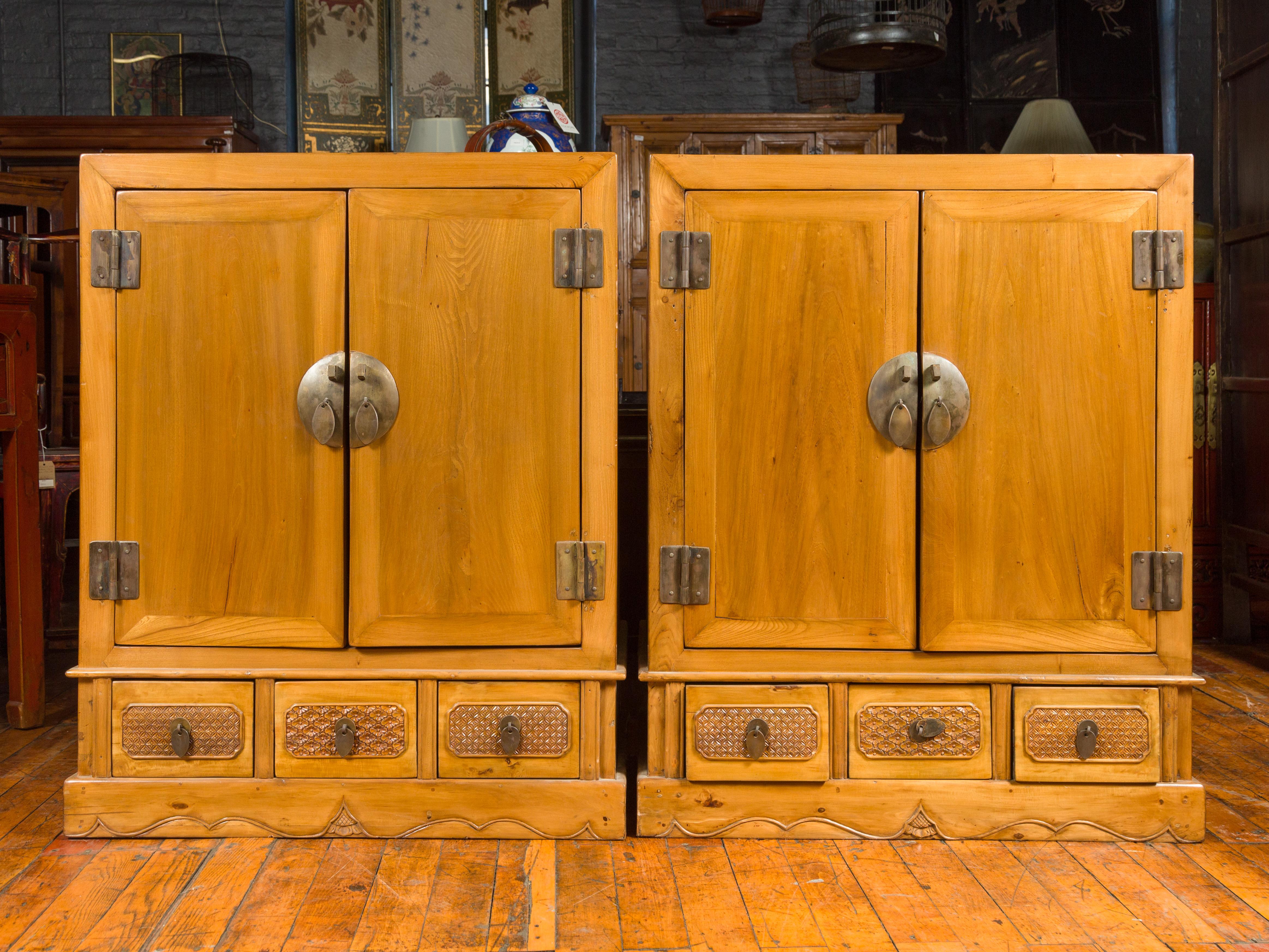 A pair of Chinese Qing Dynasty period yumu wood cabinets from the 19th century, with double doors, drawers and carved motifs. This pair of Chinese Qing Dynasty yumu wood cabinets from the 19th century offers a blend of traditional elegance and