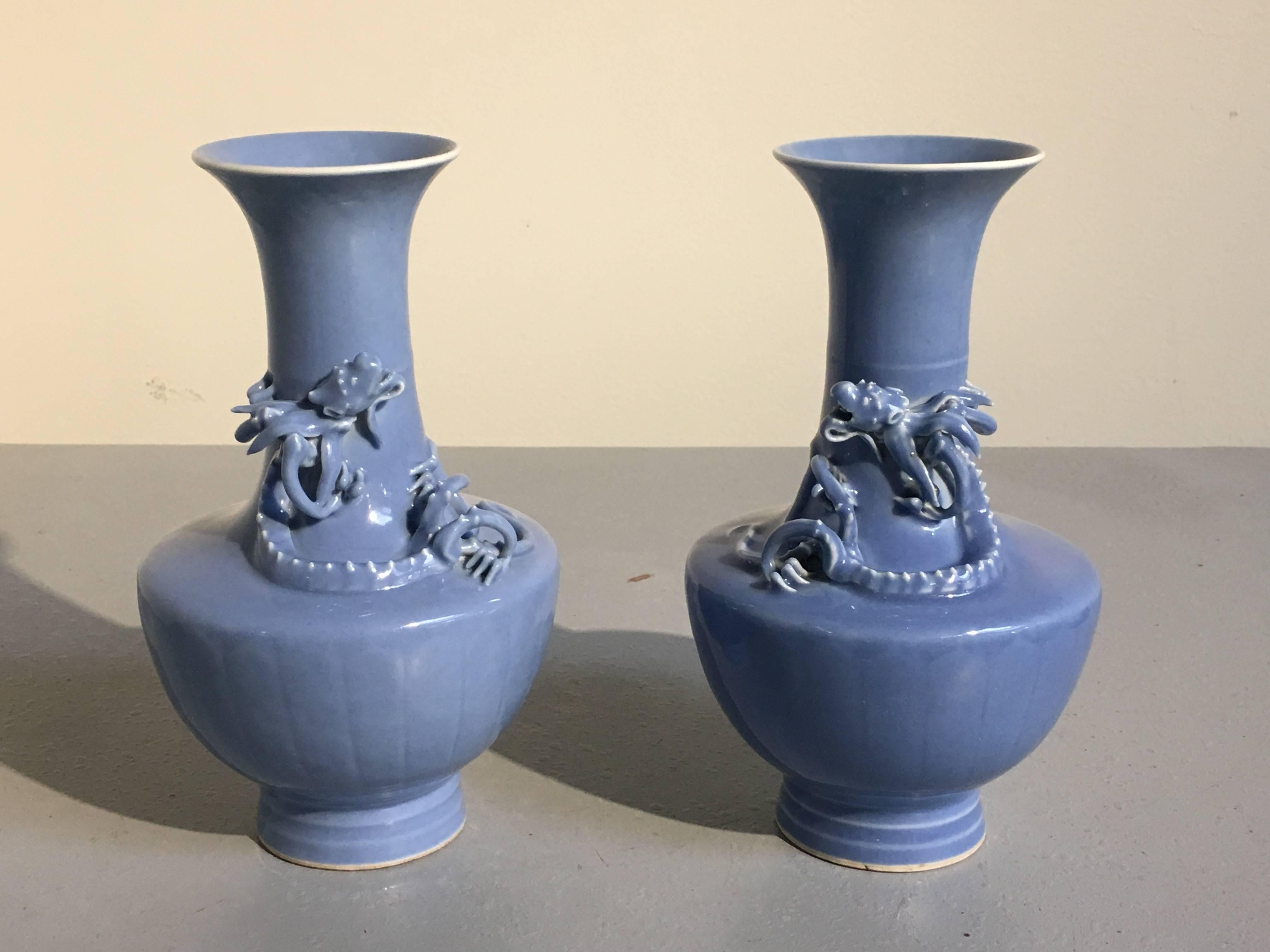 A fine matched pair of Chinese monochrome Clair de Lune glazed monochrome porcelain vases with applied molded dragons, Qing dynasty, mid to late 19th century.
The subtle blue glazed porcelain vases of unusual shape, with wide, squat bodies