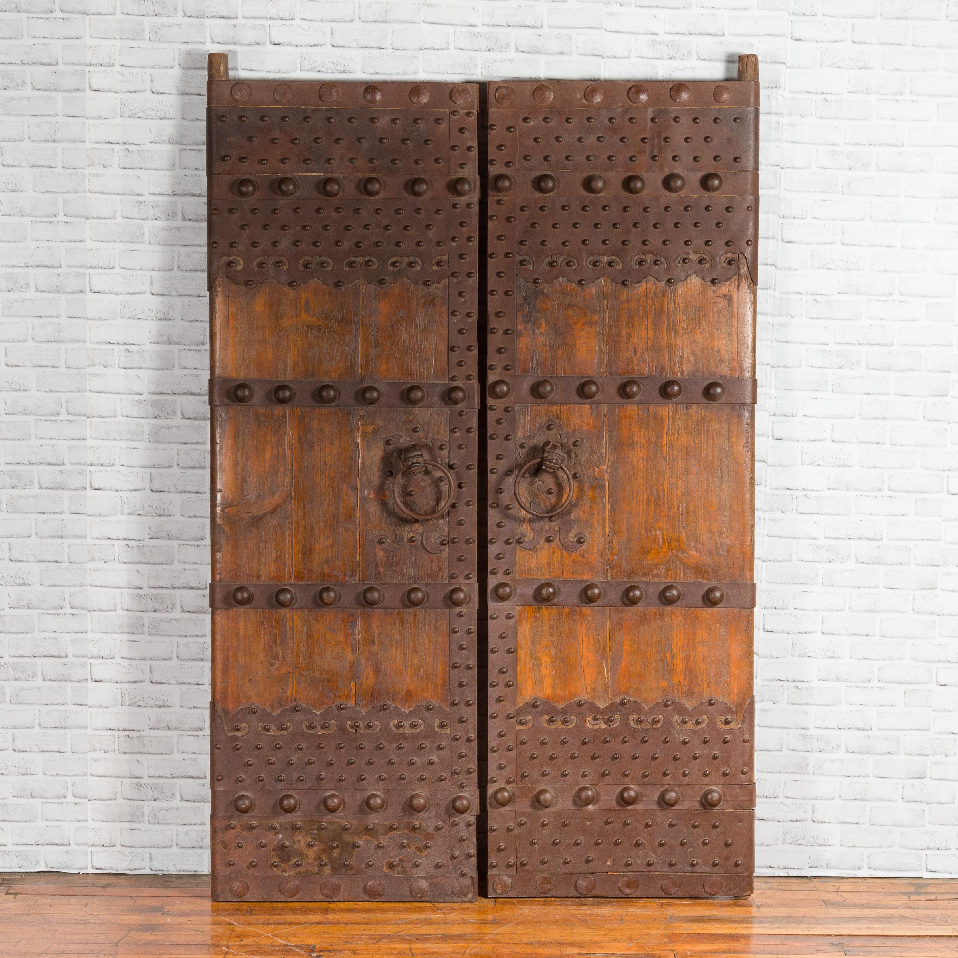 A pair of Chinese Qing Dynasty palace doors from the 19th century, with iron hardware and dark patina. 
The doors are 26