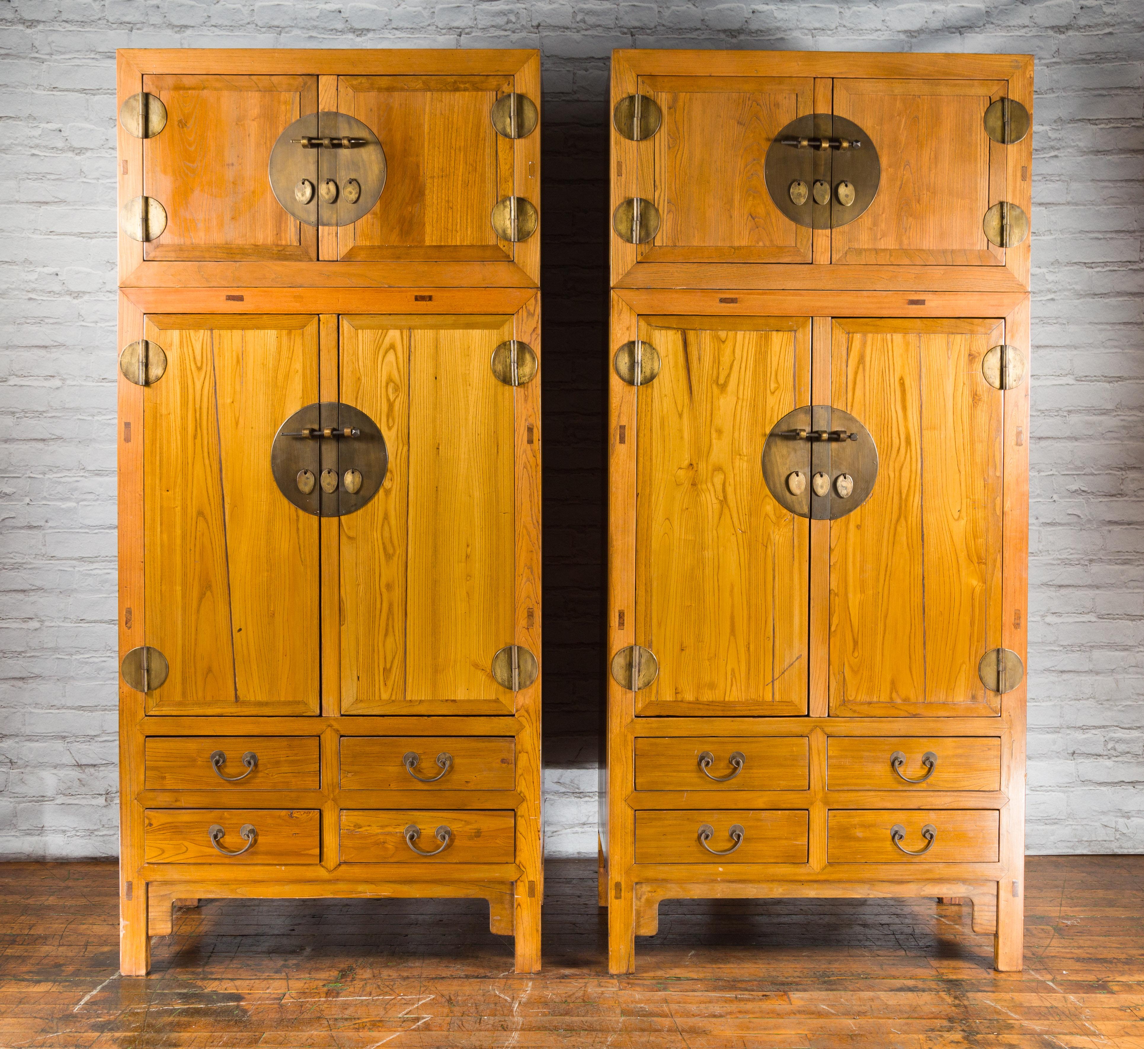 A pair of tall Chinese Qing Dynasty period compound cabinets from the 19th century made of elm wood and adorned with brass hardware. Created in China during the Qing Dynasty period in the 19th century, each of this pair of large compound wardrobes