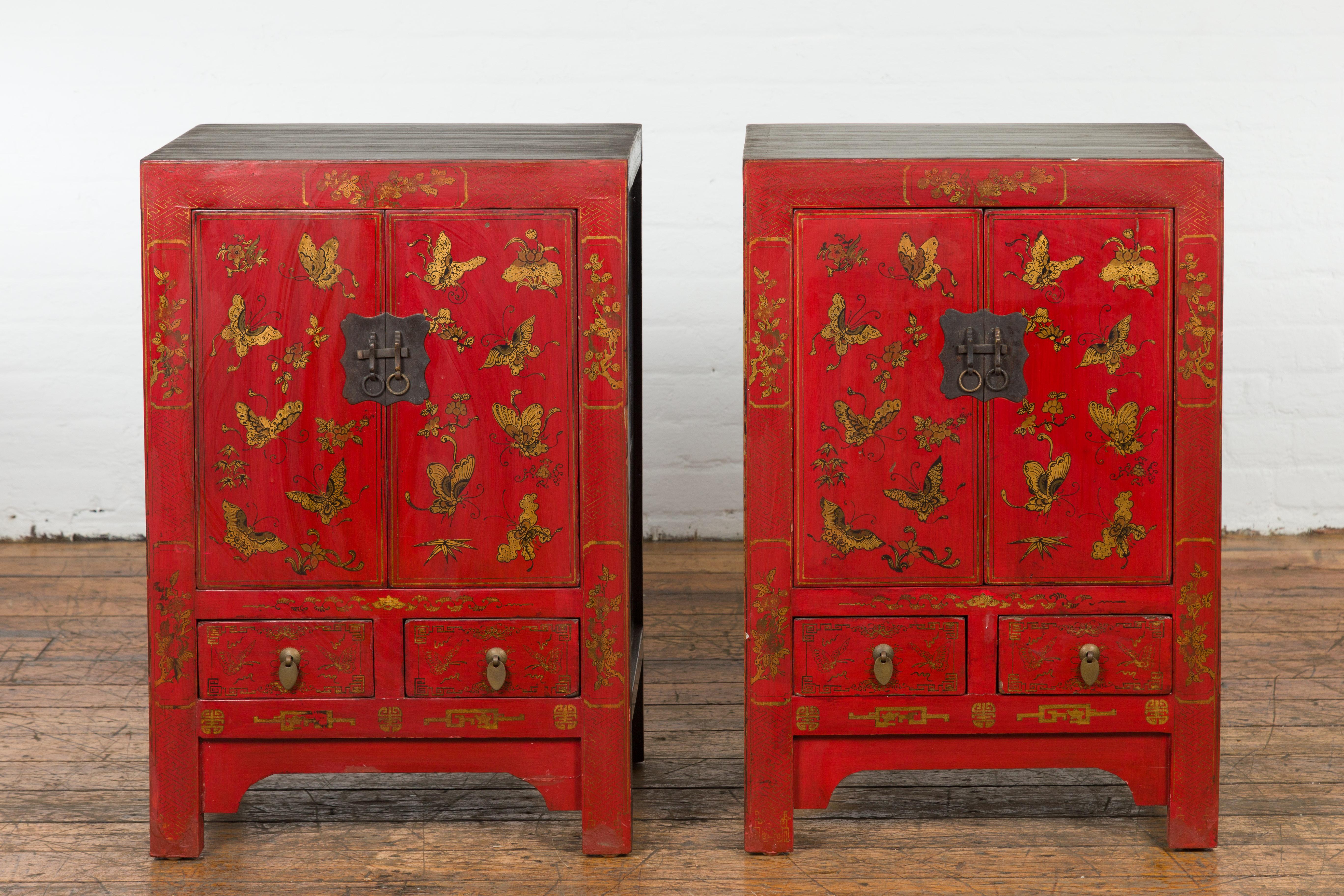 A pair of Chinese Qing Dynasty period red lacquer bedside cabinets from the 19th century, with hand painted golden butterfly and floral décor, two doors over two drawers. Created in China during the Qing Dynasty period in the 19th century, each of