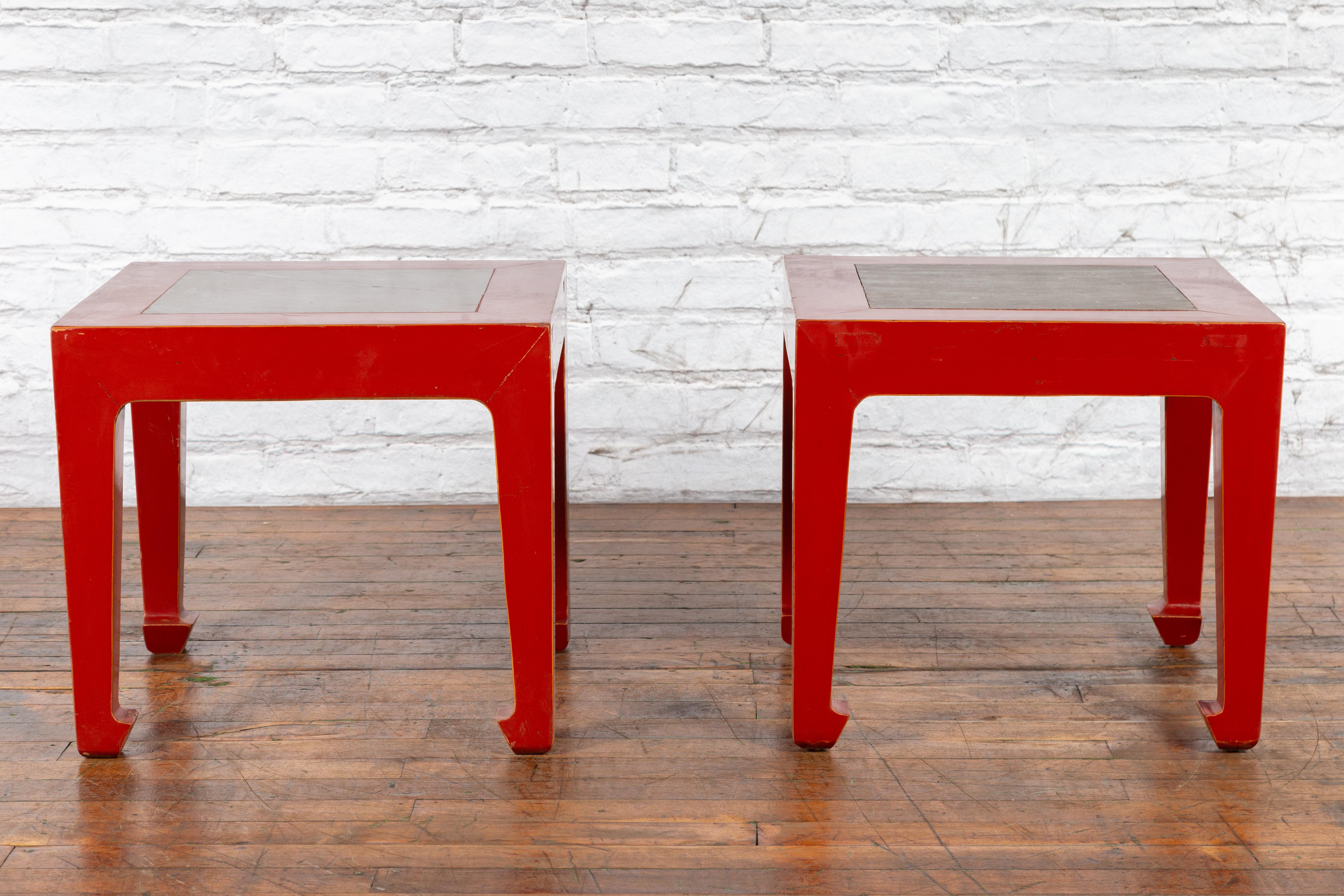 A pair of Chinese vintage side tables from the mid 20th century, with  red lacquer, Qing Dynasty period stone garden tiles tops and horse hoof legs. Created in China during the midcentury, each of this pair of side tables features a square top made