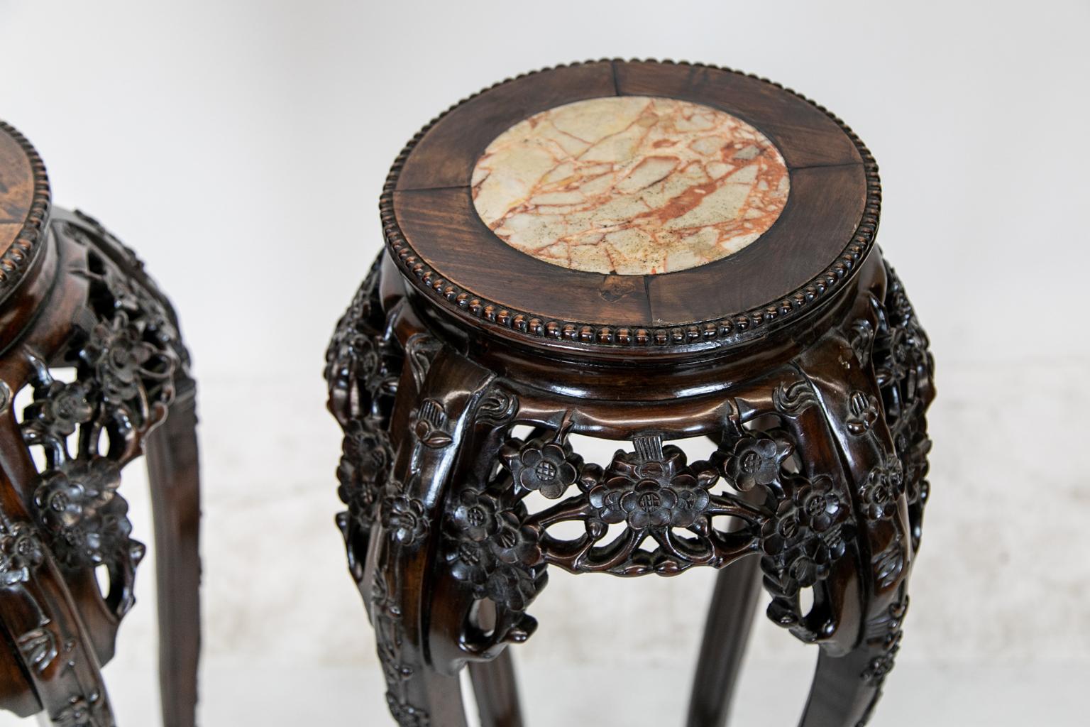Pair of Chinese rosewood stands, very rarely found as a matched pair. These have marble insets in soft beige earth tones. The aprons have carved reticulated floral motifs with a beadwork border on top. There is quarter panel banding around the