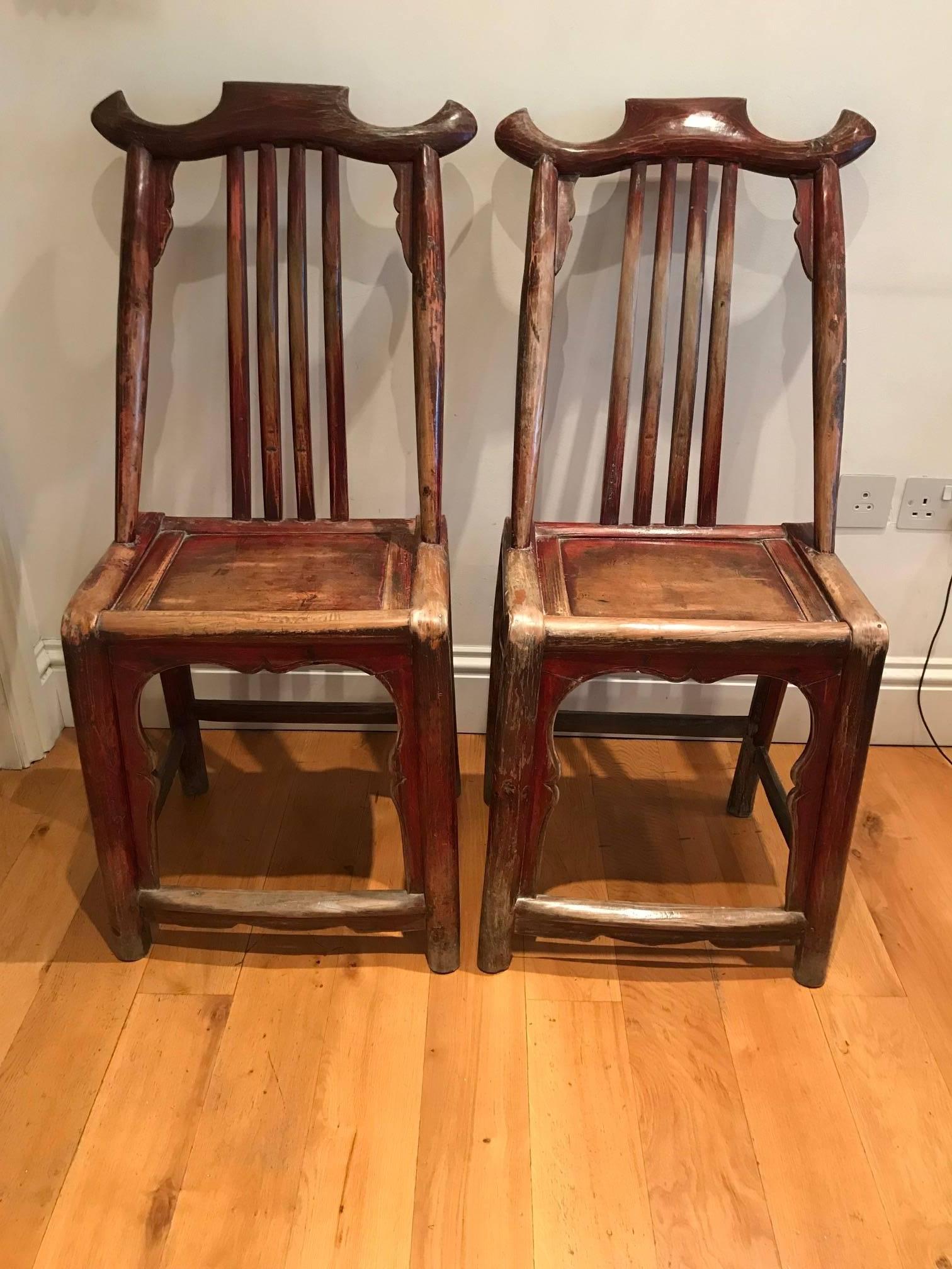 A pair of early 20th century highly decorative painted wood scroll chairs. Traces of original red coloring left with good signs of age and patination.