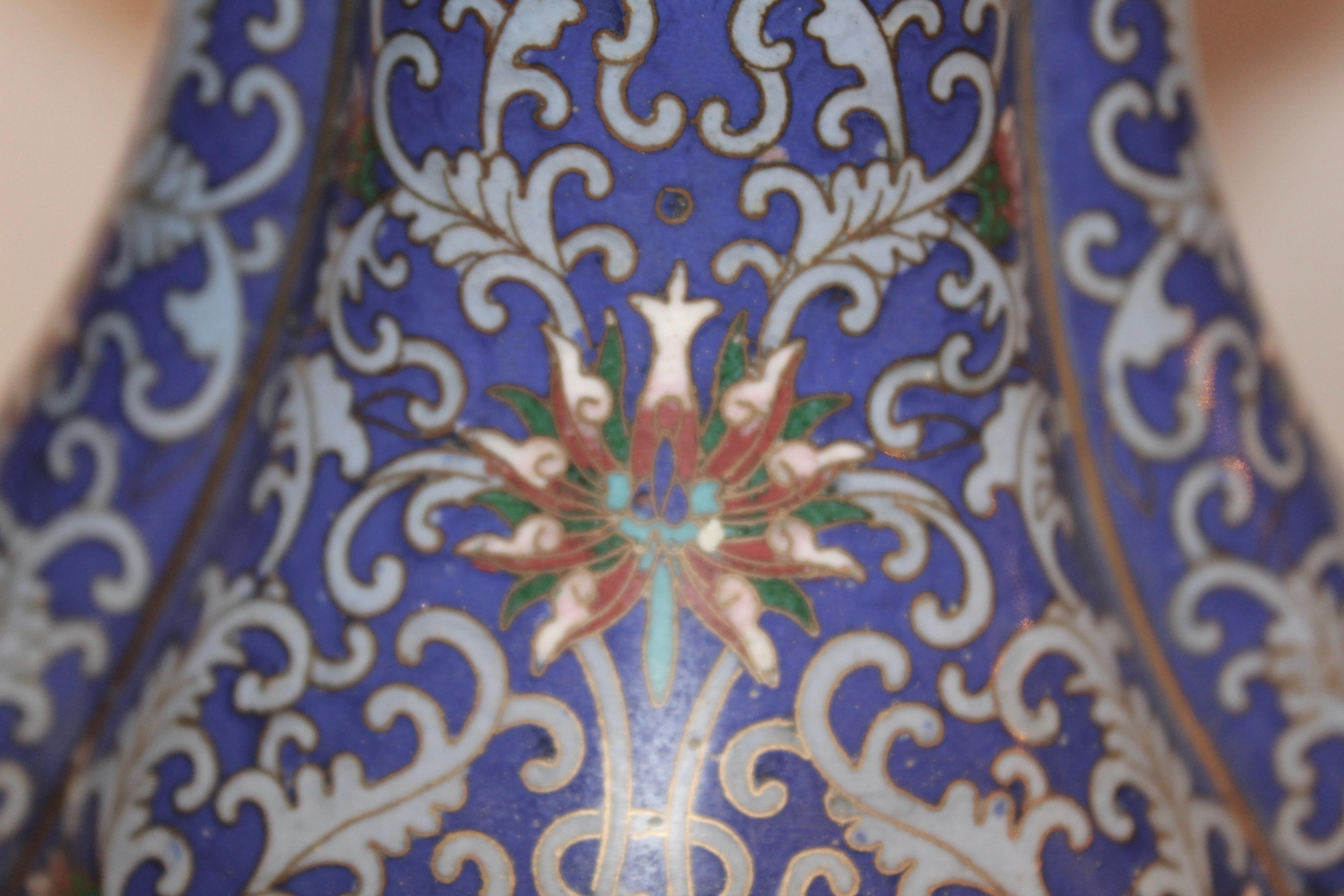 Pair of 1920s Chinese lobed shaped cloisonné enamel vases, the interior in a gold ground, and the blue exterior intricately decorated with brightly colored floral panels and arabesque ground. The base of each vase with a border of blue and red