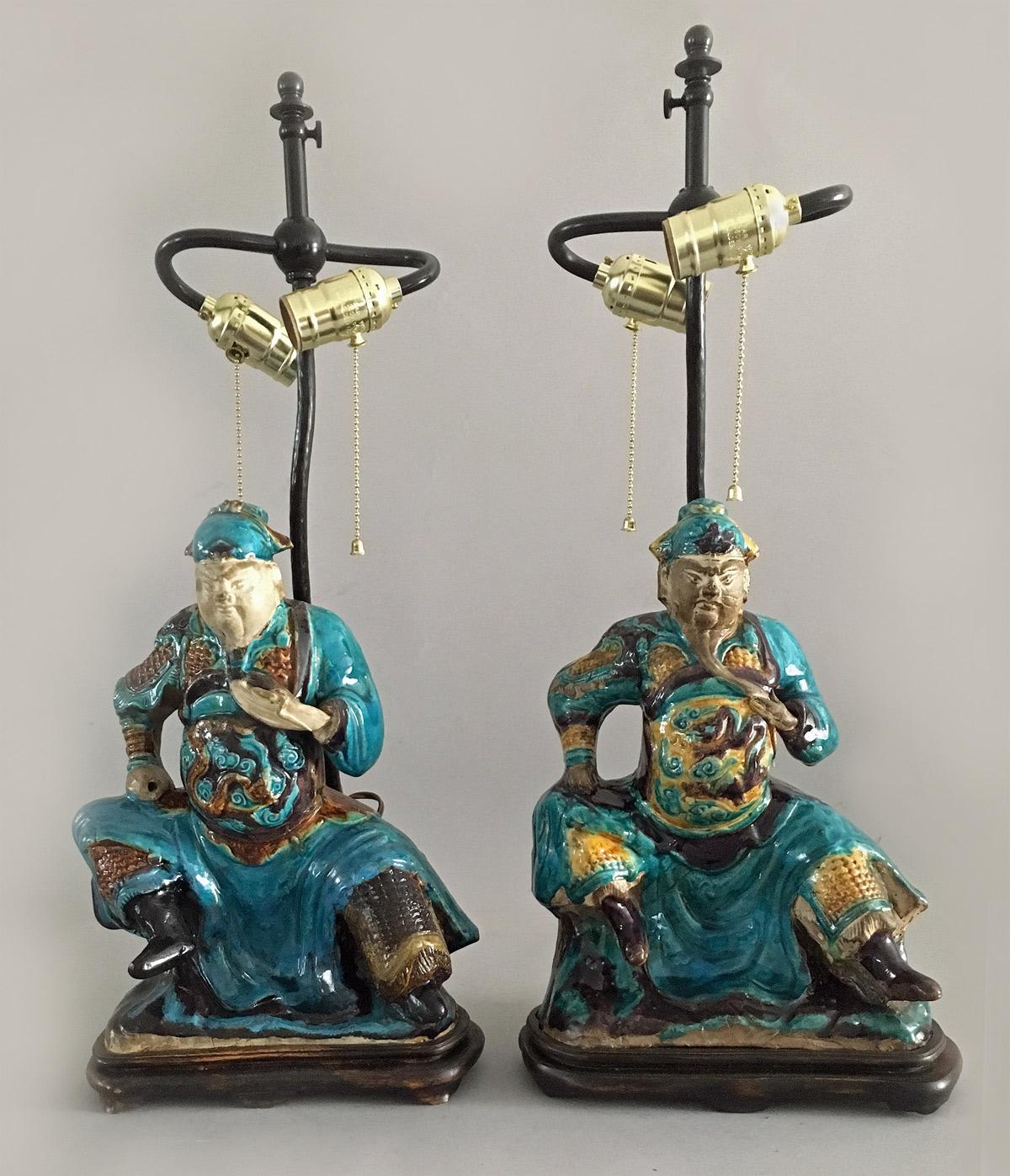 Pair of Chinese Shiwan pottery polychrome glazed figures of warriors, holding their beards, decorated in colors of turquoise, yellow and brown, mounted on wooden stands as lamps. These were originally used as roof tiles. They have brass adjustable