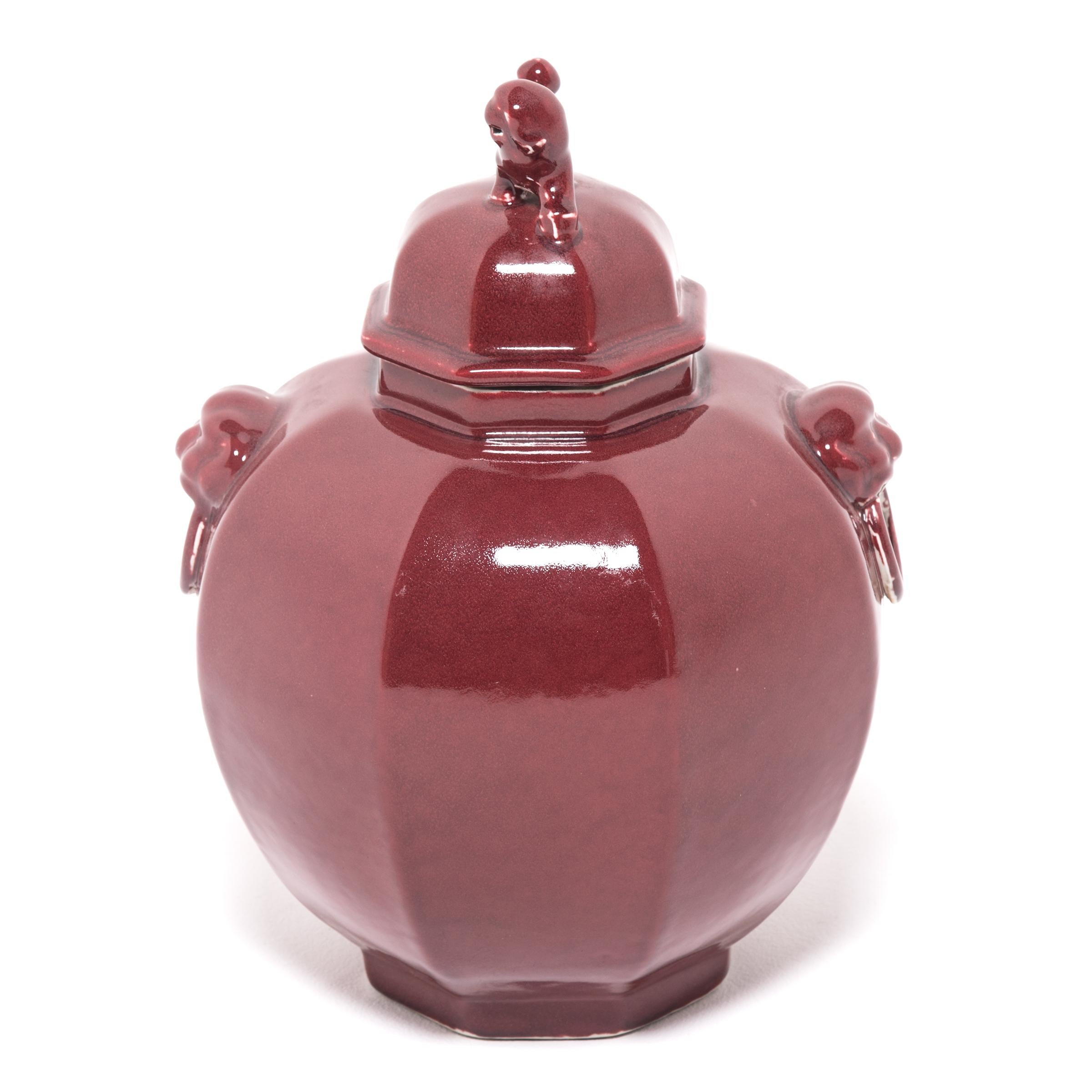 Eine satte, monochrome rote Glasur überzieht diese moderne Vase in Form eines Ingwerglases und lenkt die Aufmerksamkeit auf ihr modernes Profil und ihren skulpturalen Fu-Dog-Aufsatz. Diese mythischen, hundeähnlichen Löwen, die Shizi genannt werden,