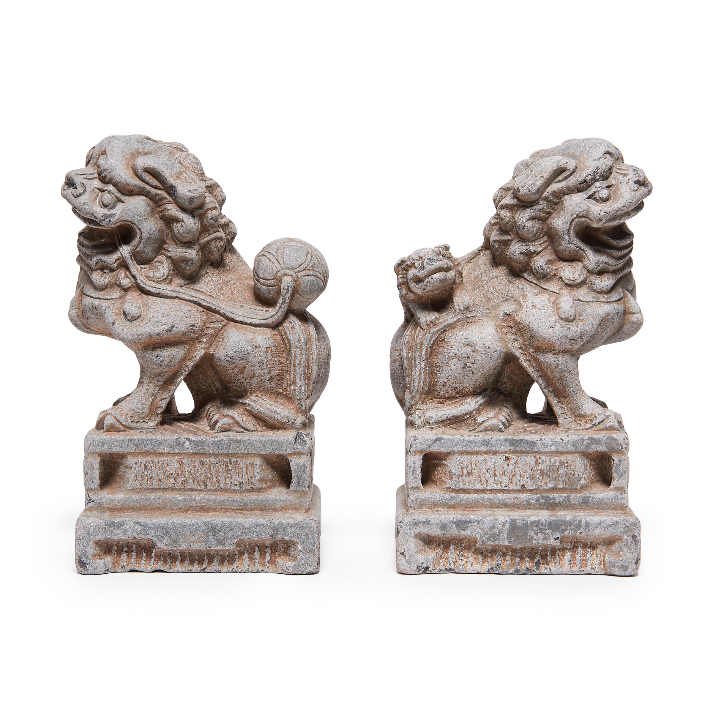 This pair of limestone fu dogs are hand-carved the traditional style, designed to flank the entryway to a home or garden. The mythical pair represents yin and yang, the balance of male and female energies. Carved with expressive facial features and