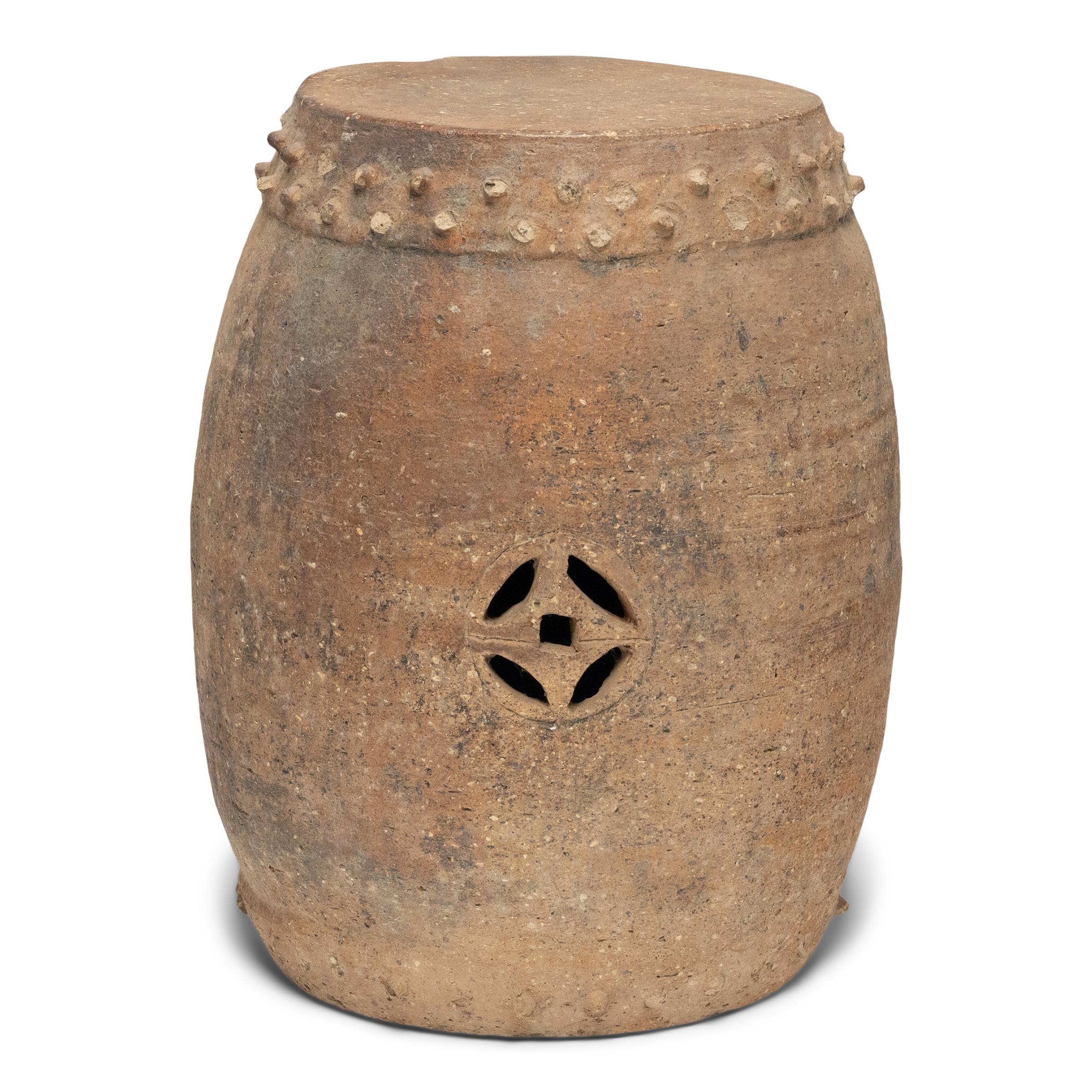 These early 20th-century terracotta garden stools honor traditional forms with a simple, drum-form shape. Ringing both the top and bottom, a pattern of boss-head nails imitates those used to stretch a skin on an actual drum, and two eternal coin