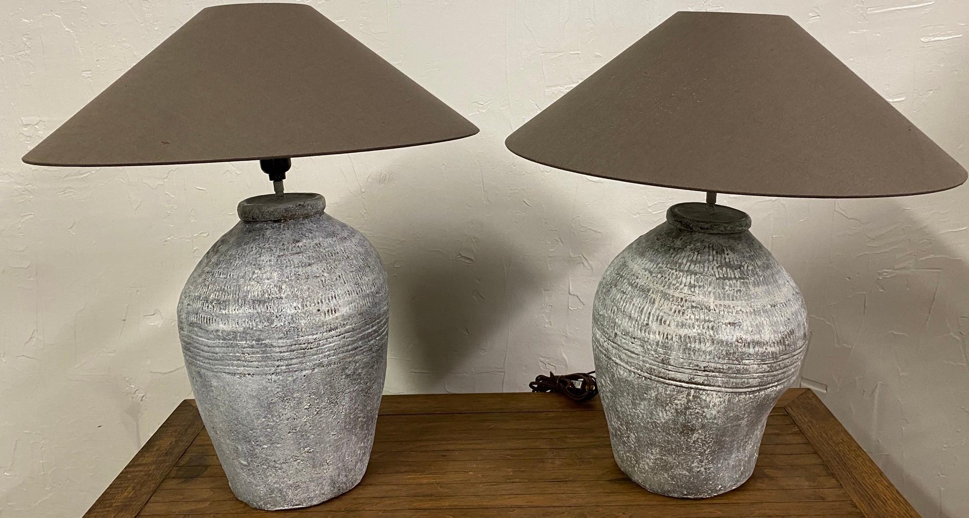 Pair of similar white painted, grey green terracotta lamp bases made from rustic vintage Chinese clay jars used for wine storage. These are not a matching pair since each of these are hand made and are not intended for decorative use. The jars are