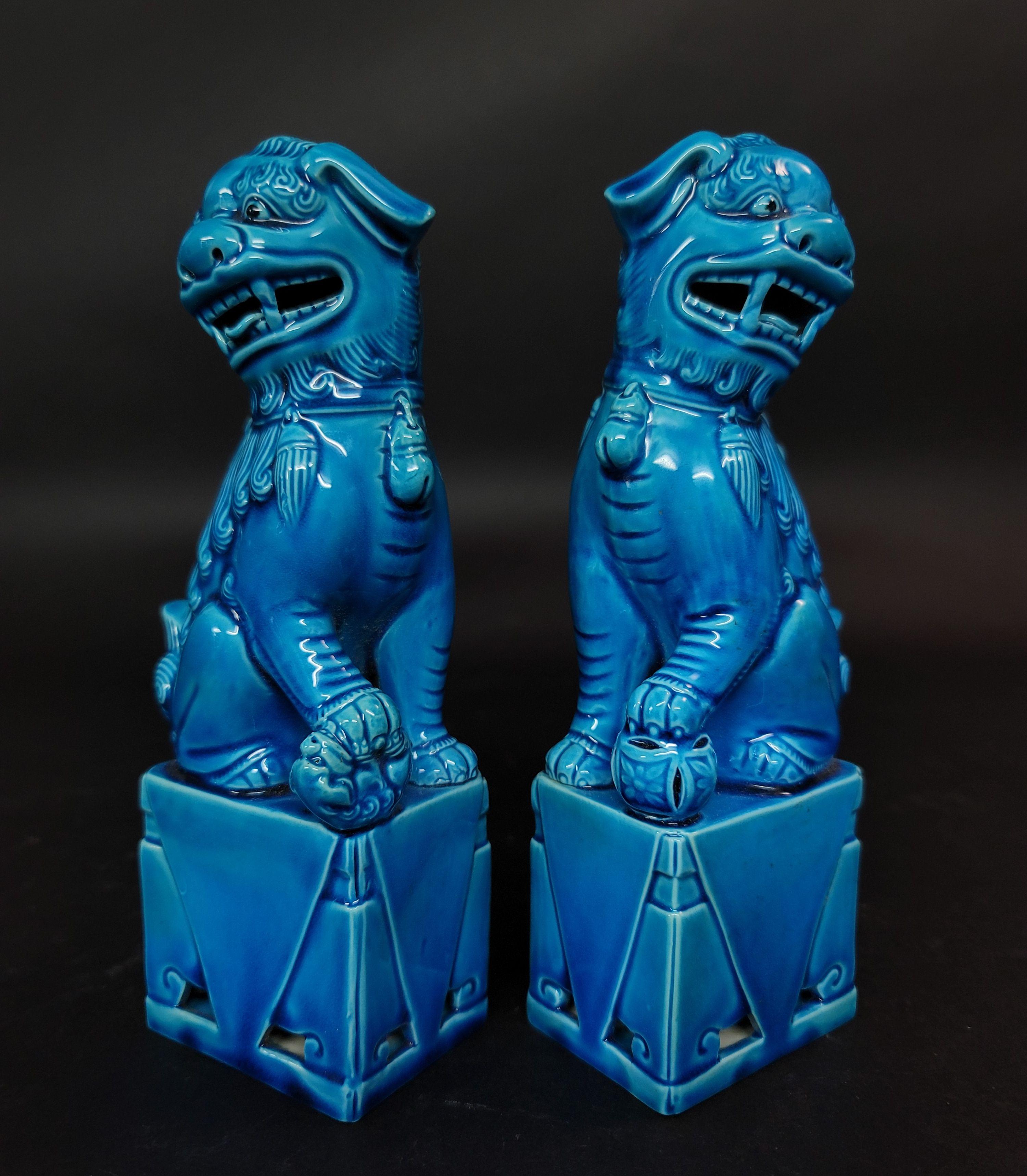 Fine and very detailed pair of Chinese turquoise glazed foo dogs from the mid 20th century. The hollow biscuit porcelain figures stand raised on a rectangular base and are looking sideways with open mouths and tongues showing teeth each with a