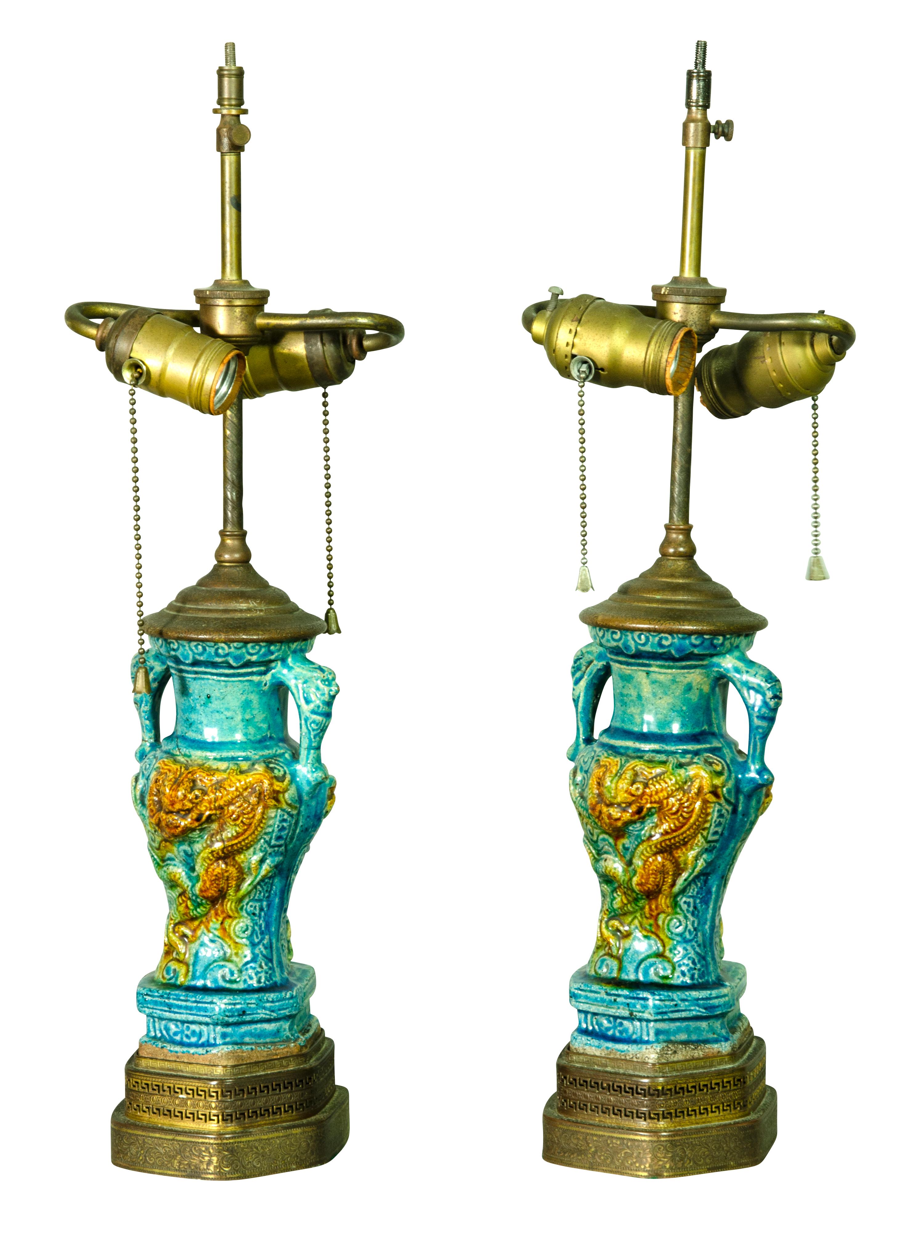 Two handle vases with central dragon relief decoration. Overall turquoise glaze. Gilt metal bases.