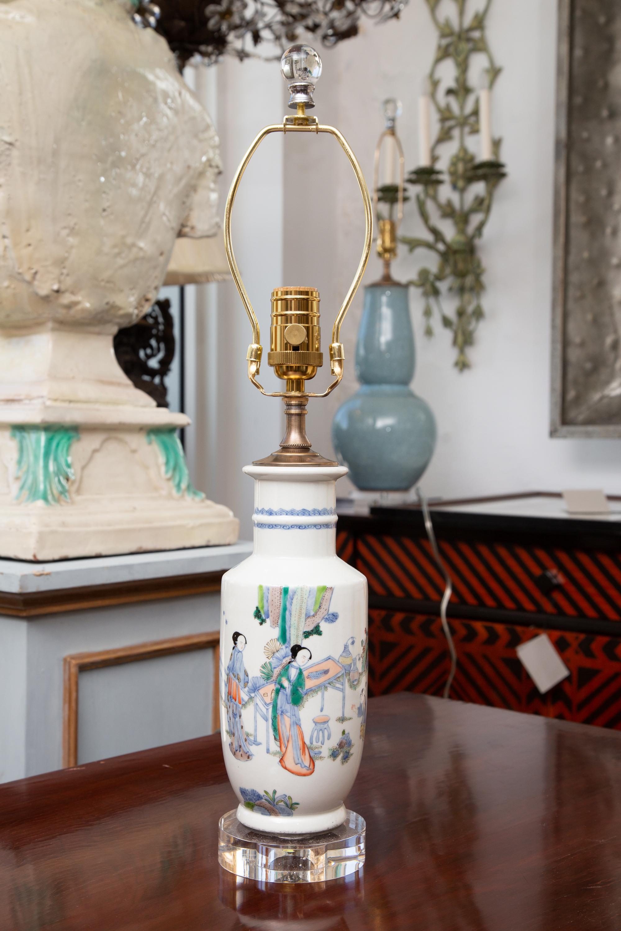 This is a pair of delicate Chinese vases depicting ladies in a domestic setting and situated on circular lucite bases. 20th century.