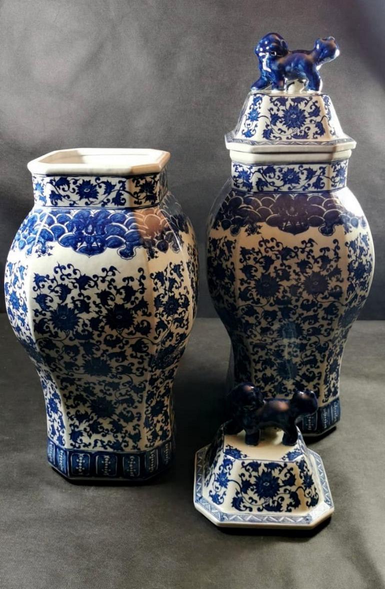 The pair of consists of two enormous hexagonal vases; they are richly decorated with elaborate cobalt blue floral designs under glass on a white background; the two lids are decorated with the sculpture of two dogs, animals full of symbolism and
