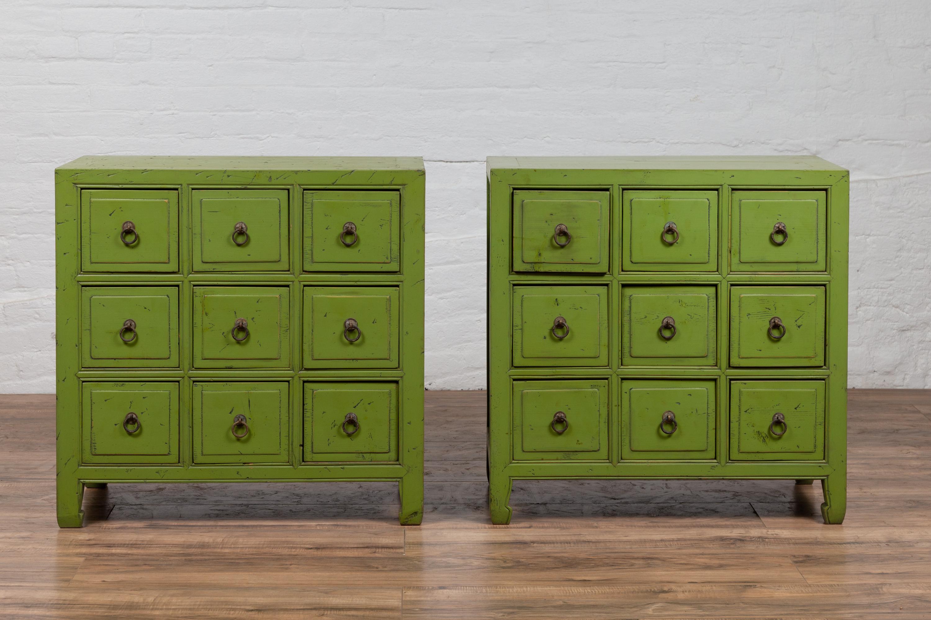 A pair of Chinese vintage green painted nine-drawer apothecary bedside chests from the mid-20th century, with black splatter. Born in China during the mid-century period, each of this charming pair of apothecary chests features a rectangular top,