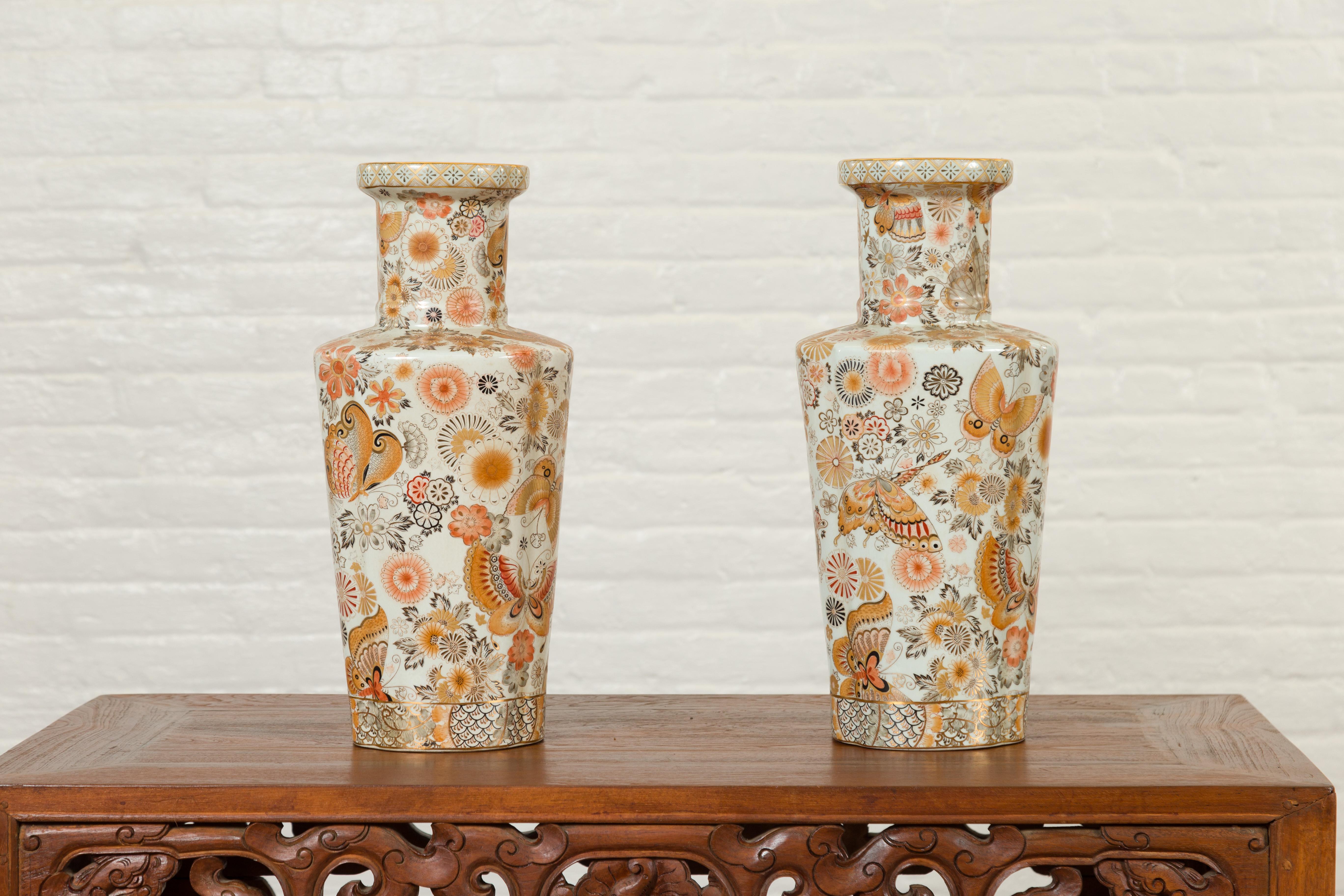 A pair of Chinese vintage Japanese Kutani style vases from the mid-20th century, with floral and butterfly decor. Created in China during the midcentury period, each of this pair of Kutani style vases attracts our attention with its golden, brown