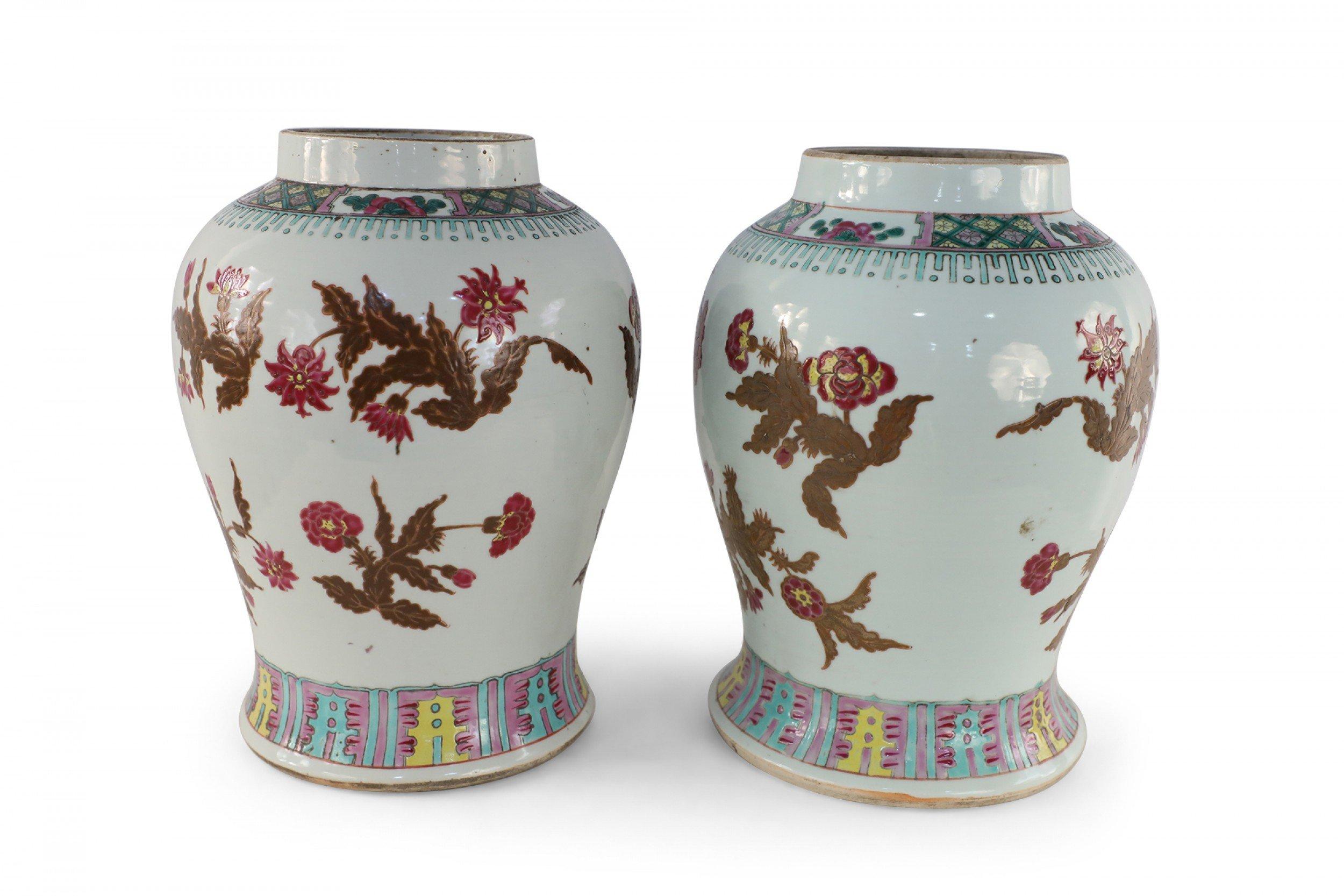 Pair of Chinese white porcelain vases decorated with umber and pink floral motifs wrapping the bulbous forms, accented in blue, pink and yellow patterned bands around the tops and bases (Priced as pair).
 