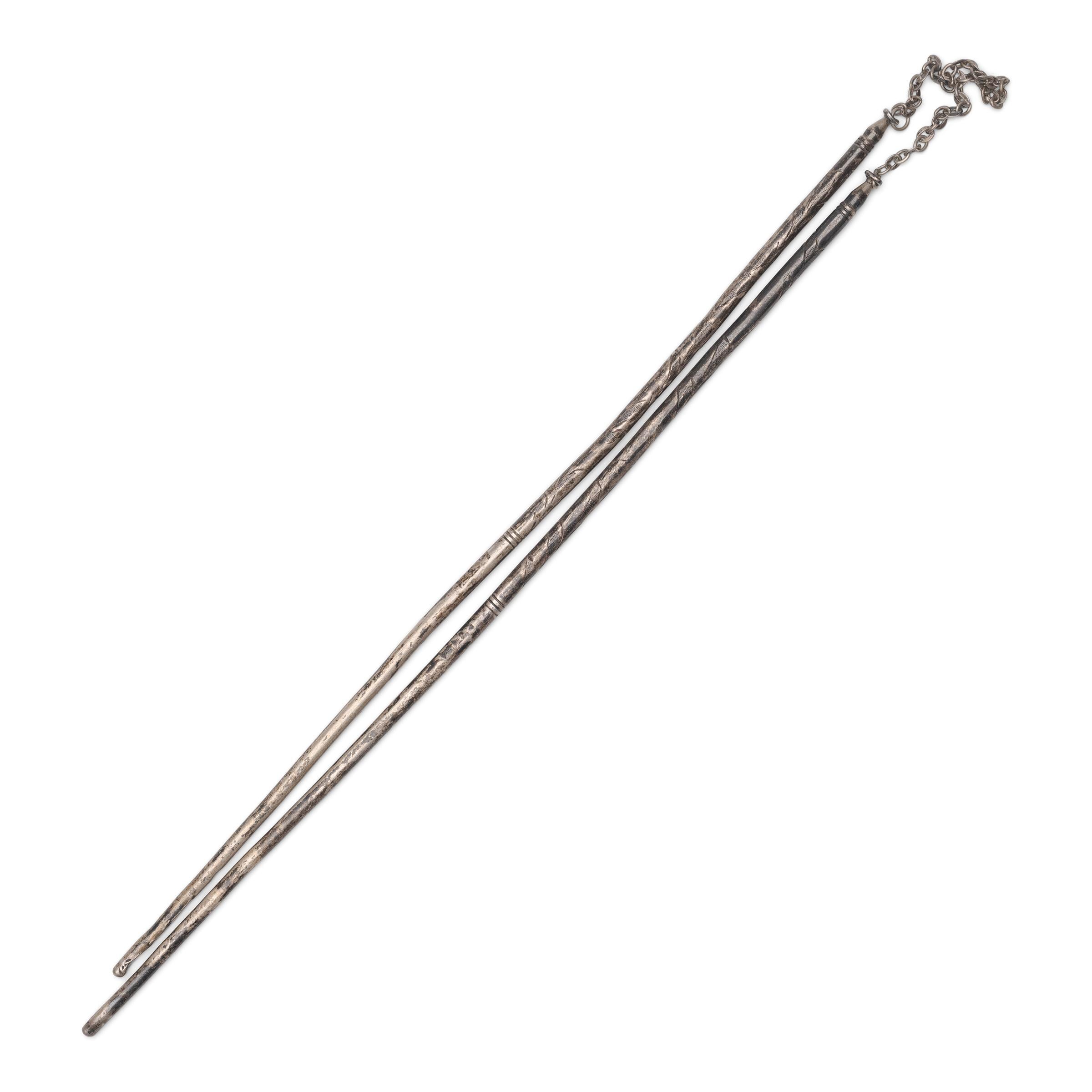 A pair of white brass chopsticks for moving burning coals in a hibachi or hand-warmer. Such chopsticks were also used to safely touch opium pipe bowls or tools that had been heated by an opium lamp. The thin metal chopsticks are etched with floral
