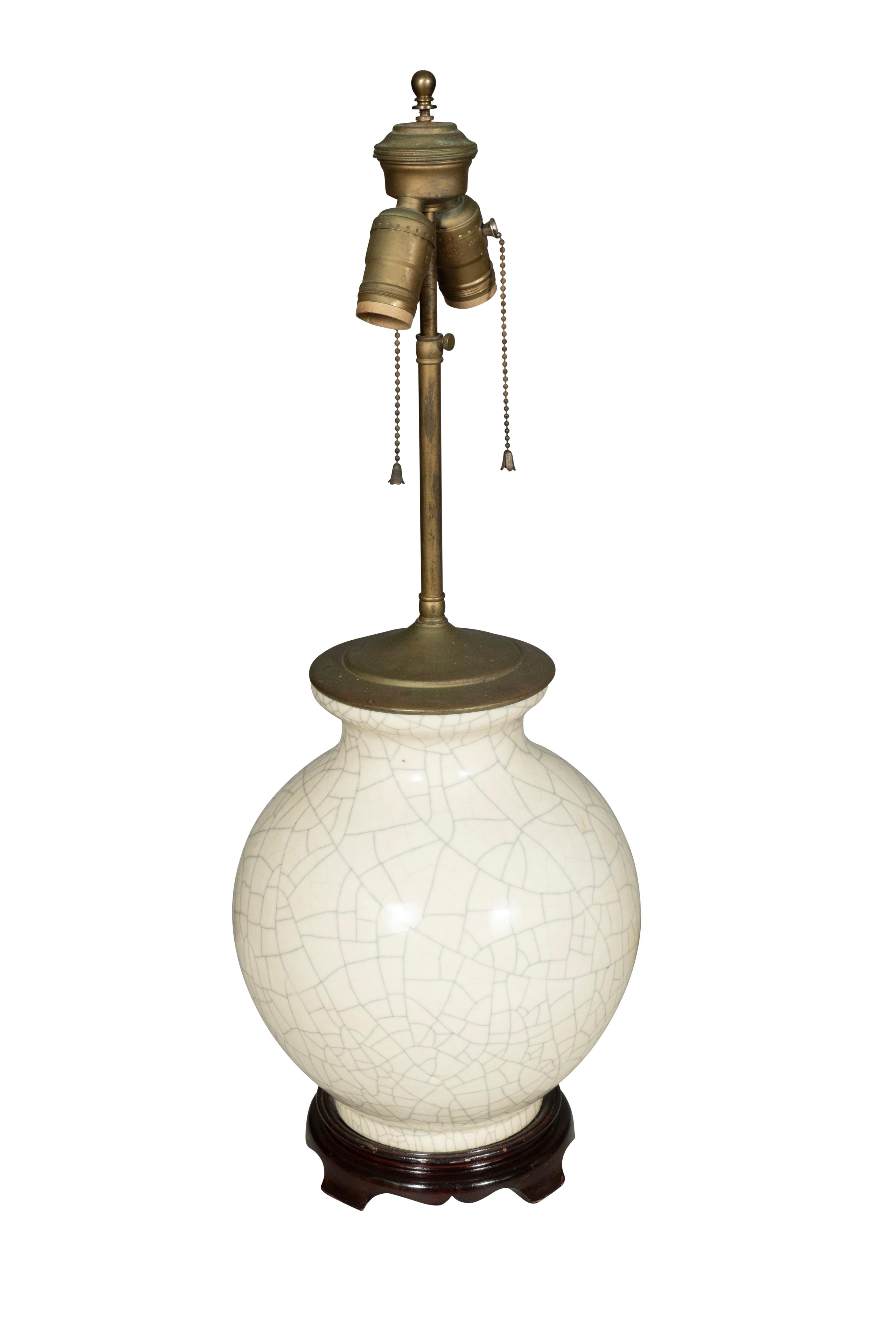Chaque forme globulaire avec une surface craquelée de couleur crème.. Deux lampes avec base en bois et abat-jour inclus.