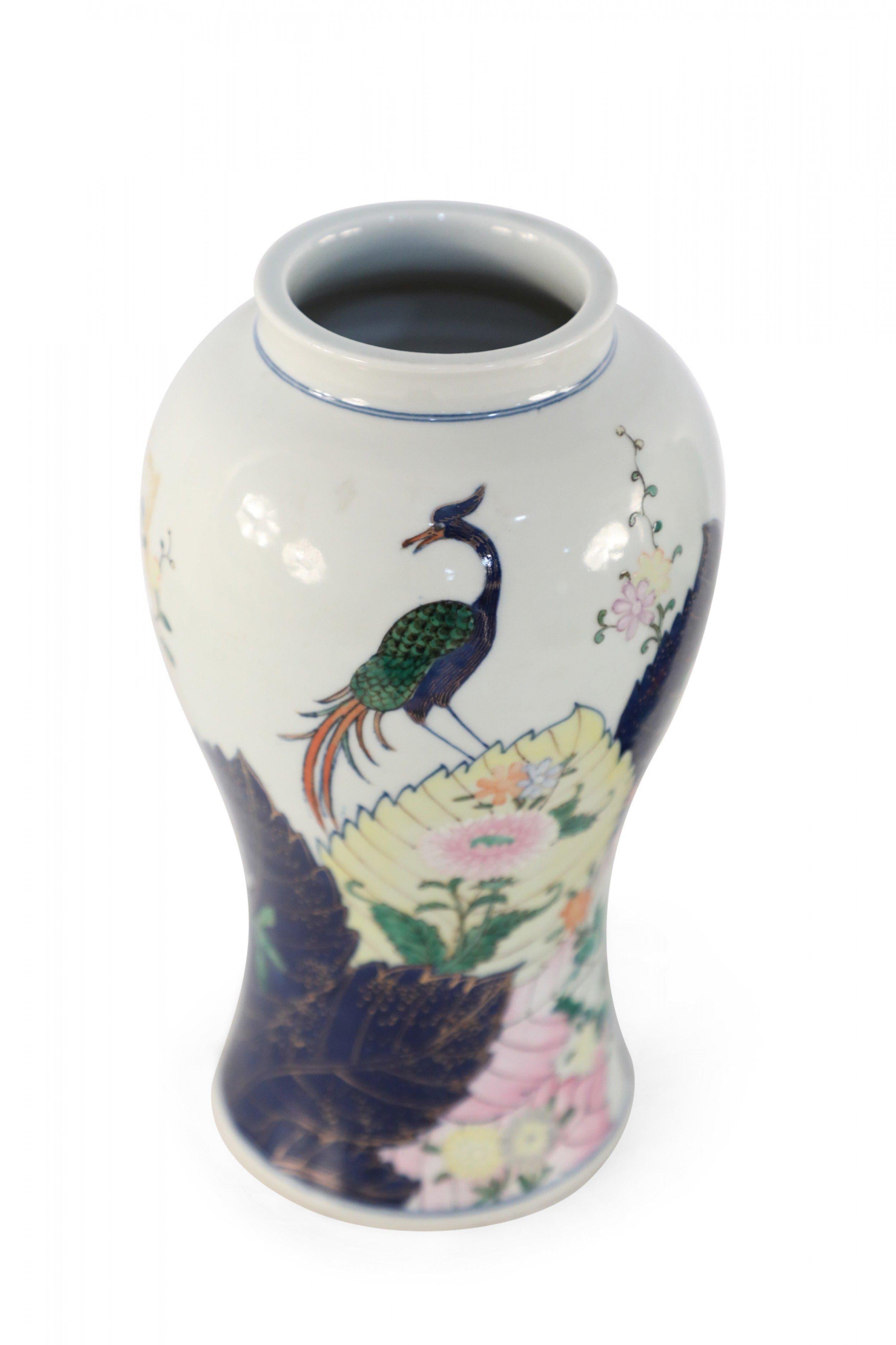 Pair of Chinese white porcelain vases with urn-shaped forms decorated in large scale dark blue leaves outlined in gold, amid green, yellow and pink foliage and flora topped with blue peacocks (priced as pair).
   
