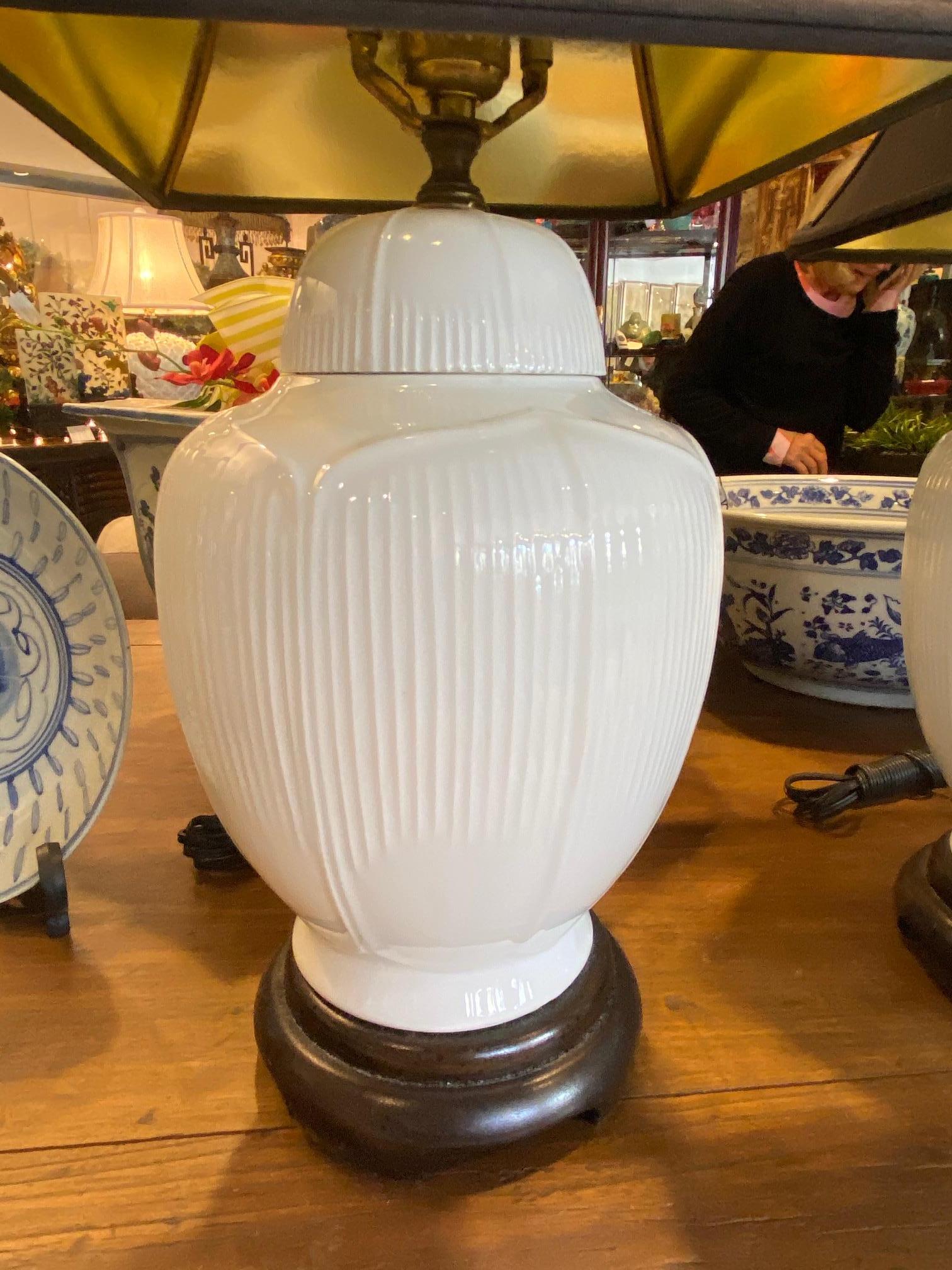 This pair of Chinese Blanc de Chine white porcelain (having a touch of slight green) ginger jar lamps molded base design with lotus leaves converted into lamps, porcelain, brass and wood bases finals having birds and tree branches circa 1960s with