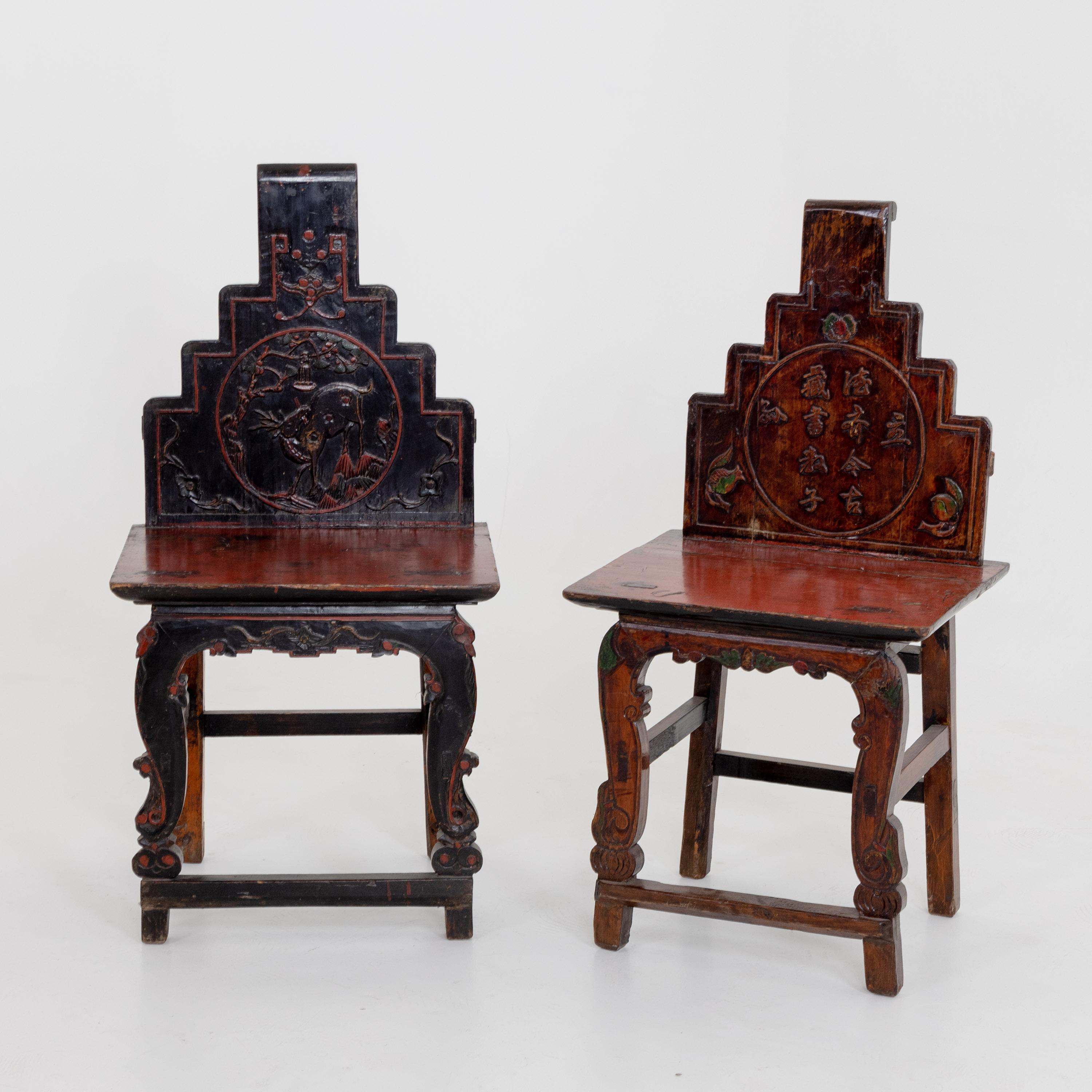 Pair of Chinese wooden chairs with stepped backs and carved decoration.
