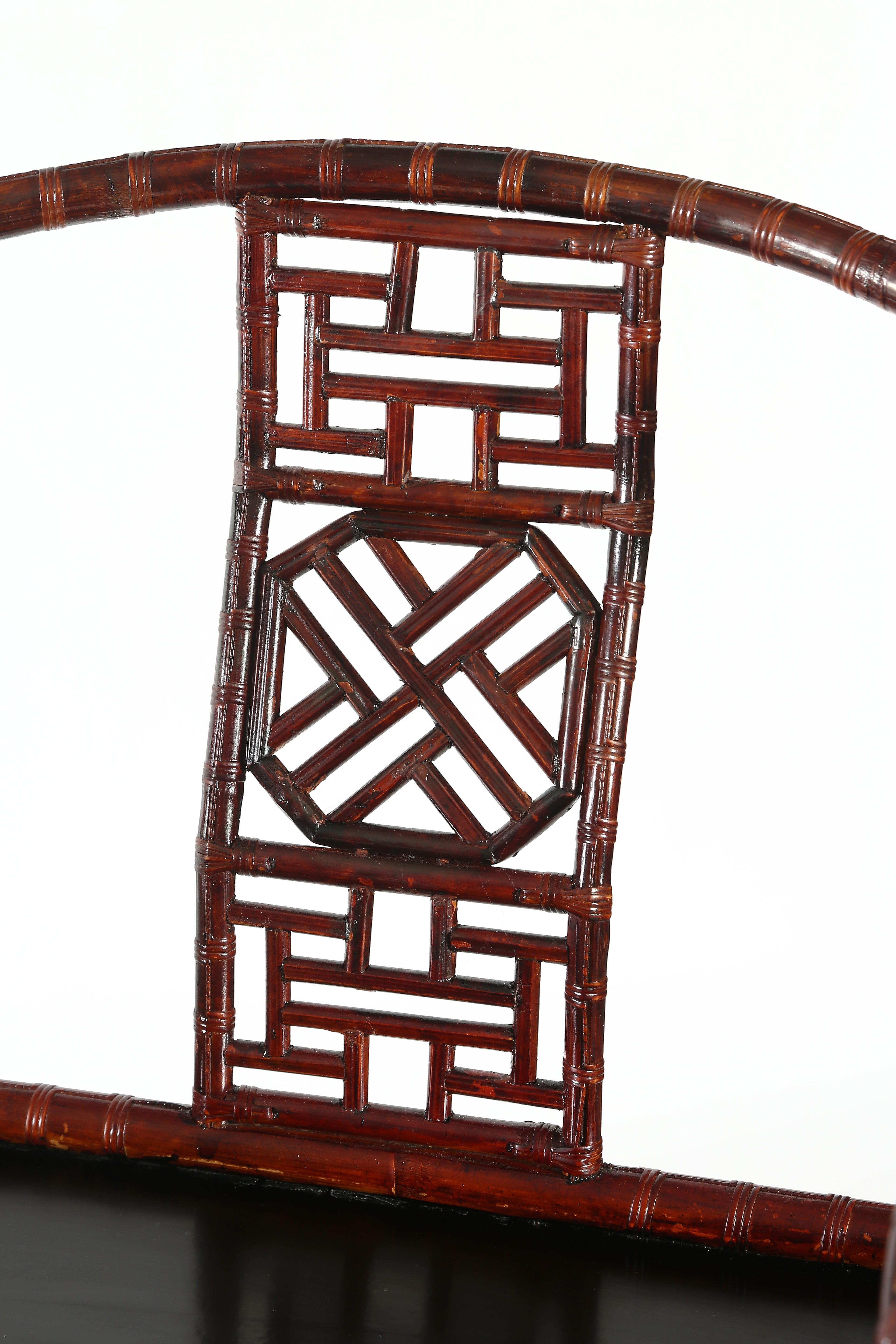 The circular-sectioned top rail curving in horseshoe shape to form the arms and extending to the hooked hand grips, supported on a S-curved back splat with a three-sectioned lattice panel, straight back and front posts extending to form the legs,