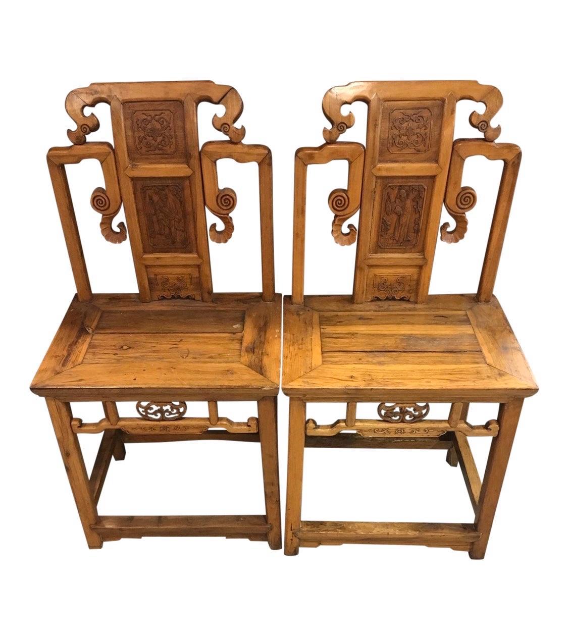 Elegant pair of two matching heavily carved Chinese altar chairs. Both have intricate carvings and date to the late 20th century.