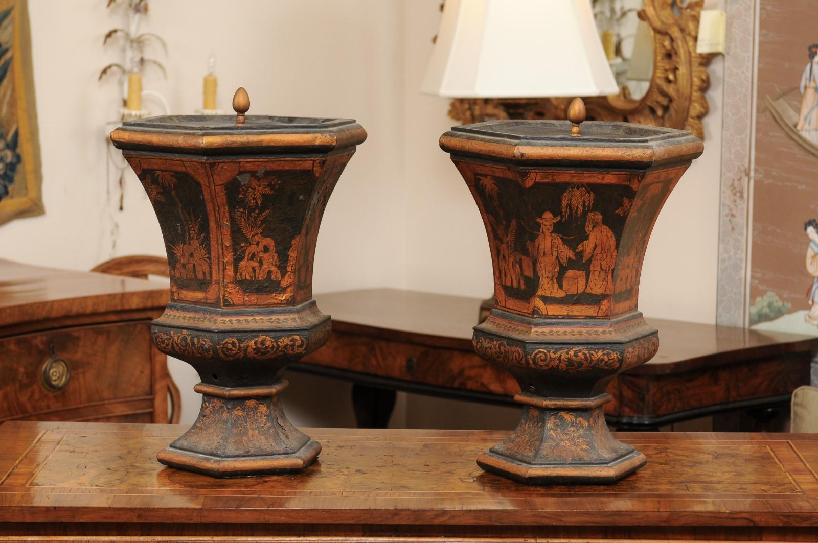 Une paire de grandes urnes à couvercle en tole noire et or, décorées de chinoiseries, datant de la fin du XIXe siècle.