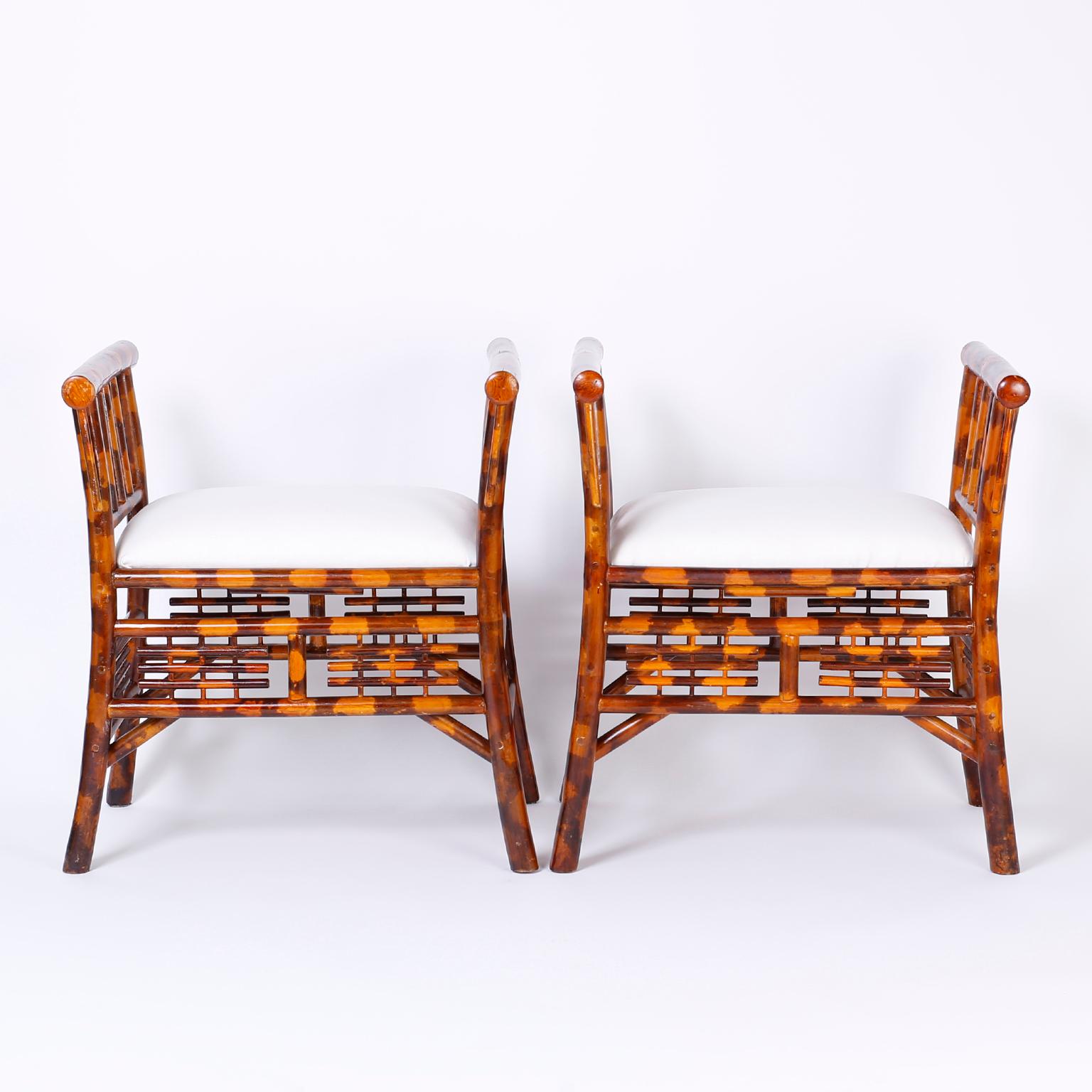 Stand out pair of benches with a chic Asian modern form, featuring unusual high arms, alluring faux burnt bamboo finish, and decorative chinoiserie style panels.