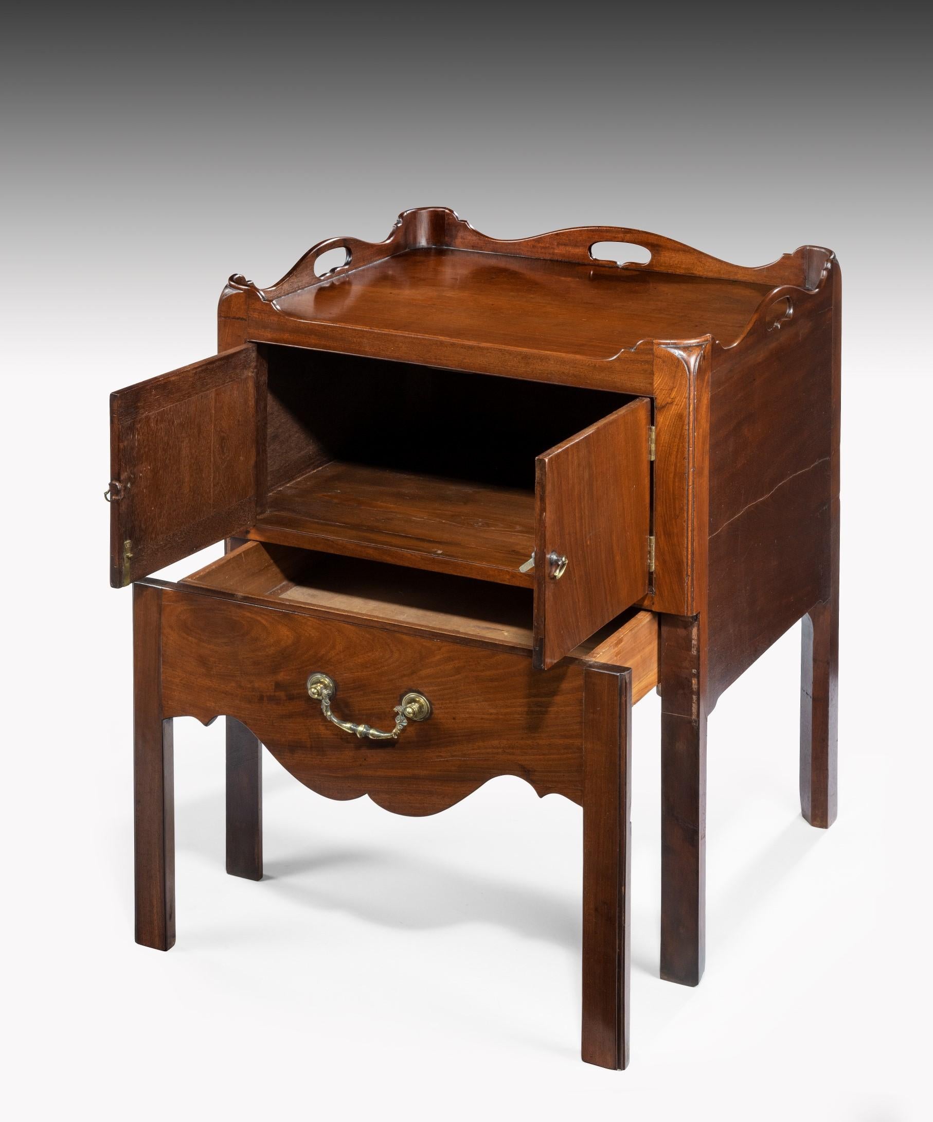 A fine pair of Georgian Chippendale period mahogany tray top commodes; the commode's shaped gallery pierced with carrying handles above a pair of cupboard doors and a pull-out drawer below with a Rococo swan neck handle; raised on square chamfered