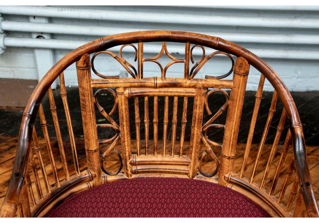 Finely crafted Chinese Chippendale style bamboo armchairs with scrolled panels framing the slatted backs. With curved slatted sides and arch shaped arm supports. The caned seats with different fabric covered cushions. Slatted front and side aprons