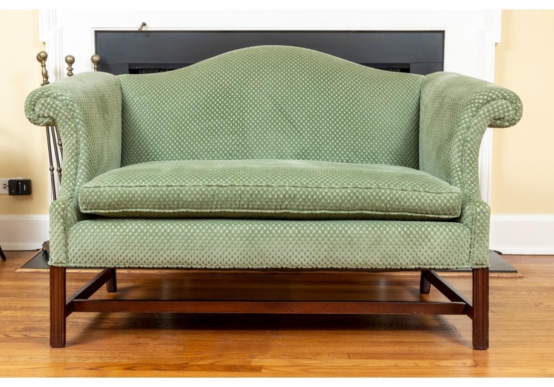 Fine Pair of Chippendale style Mahogany framed, upholstered settee's with loose seat cushions. Finished with a textural green upholstery, the settees feature rolled arms, a serpentine form back rail and exposed finished mahogany legs and stretcher