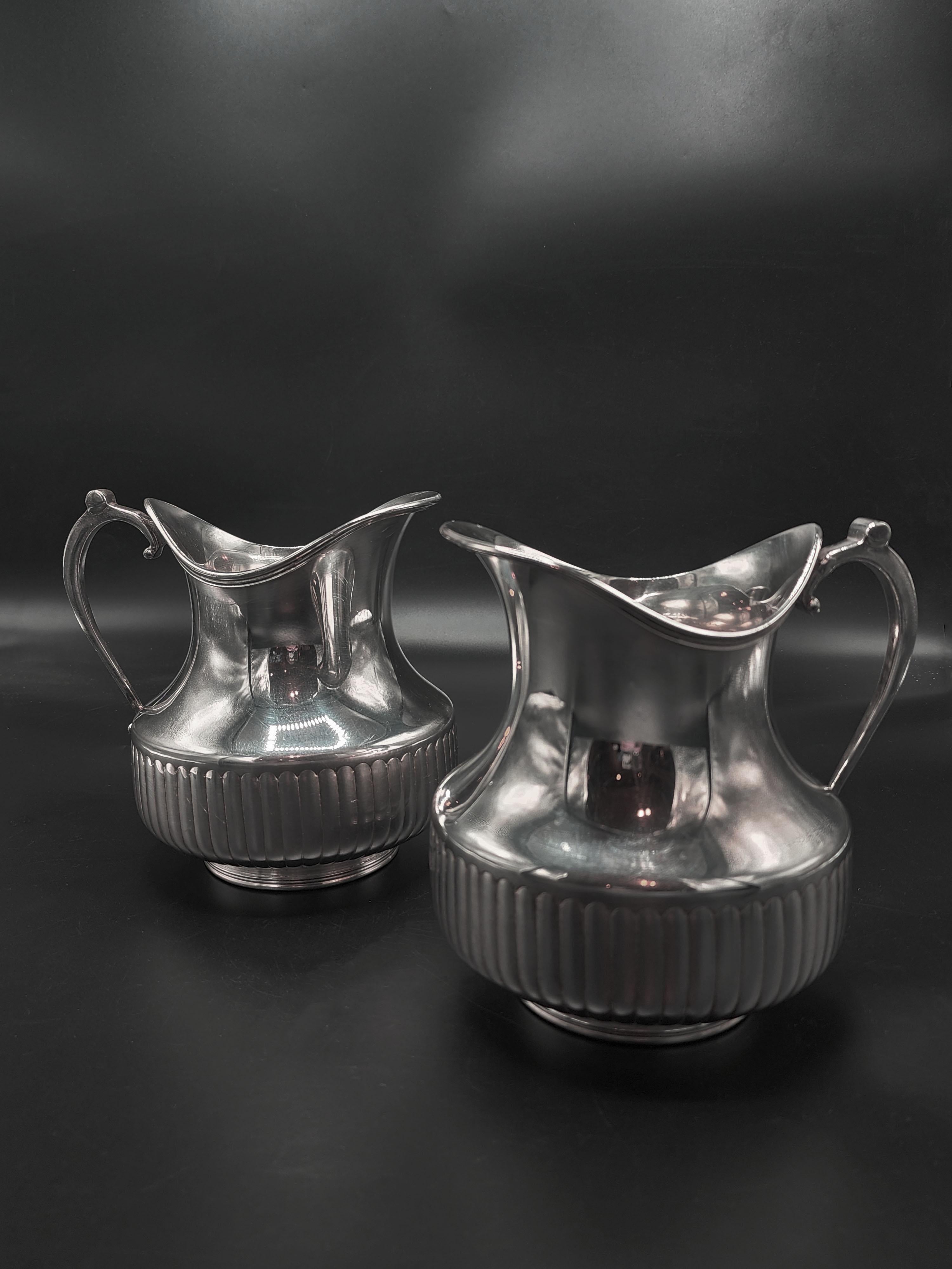 Pareja de jarras de metal plateado Christofle
Precioso juego de jarras de metal plateado con una base estriada que le da un toque elegante y clásico. El cuerpo de la jarra es liso y brillante, el asa es curvada y ergonómica, diseñada para un agarre