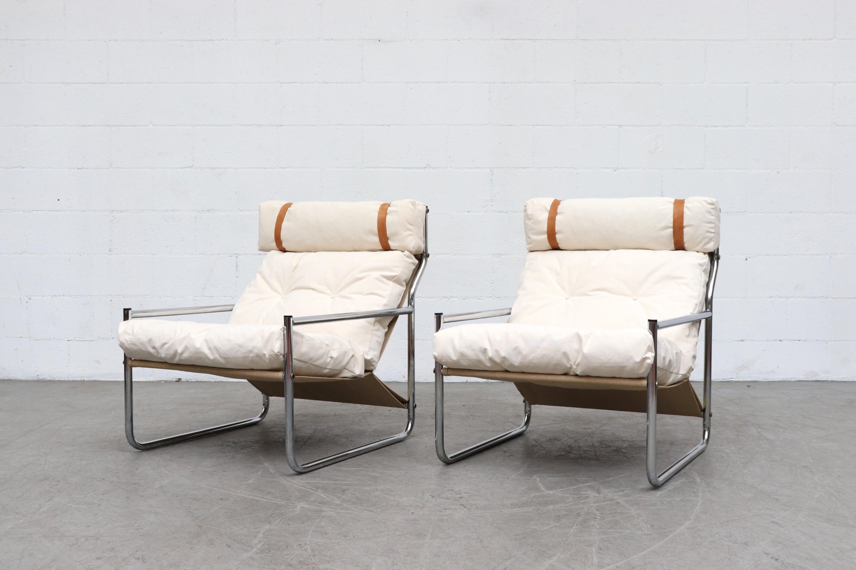 Pair of chrome and canvas lounge chairs with leather strapped headrests. Newly upholstered in white canvas with new leather straps holding the headrest pillows, original linen sling support and frame in original condition with some signs of wear