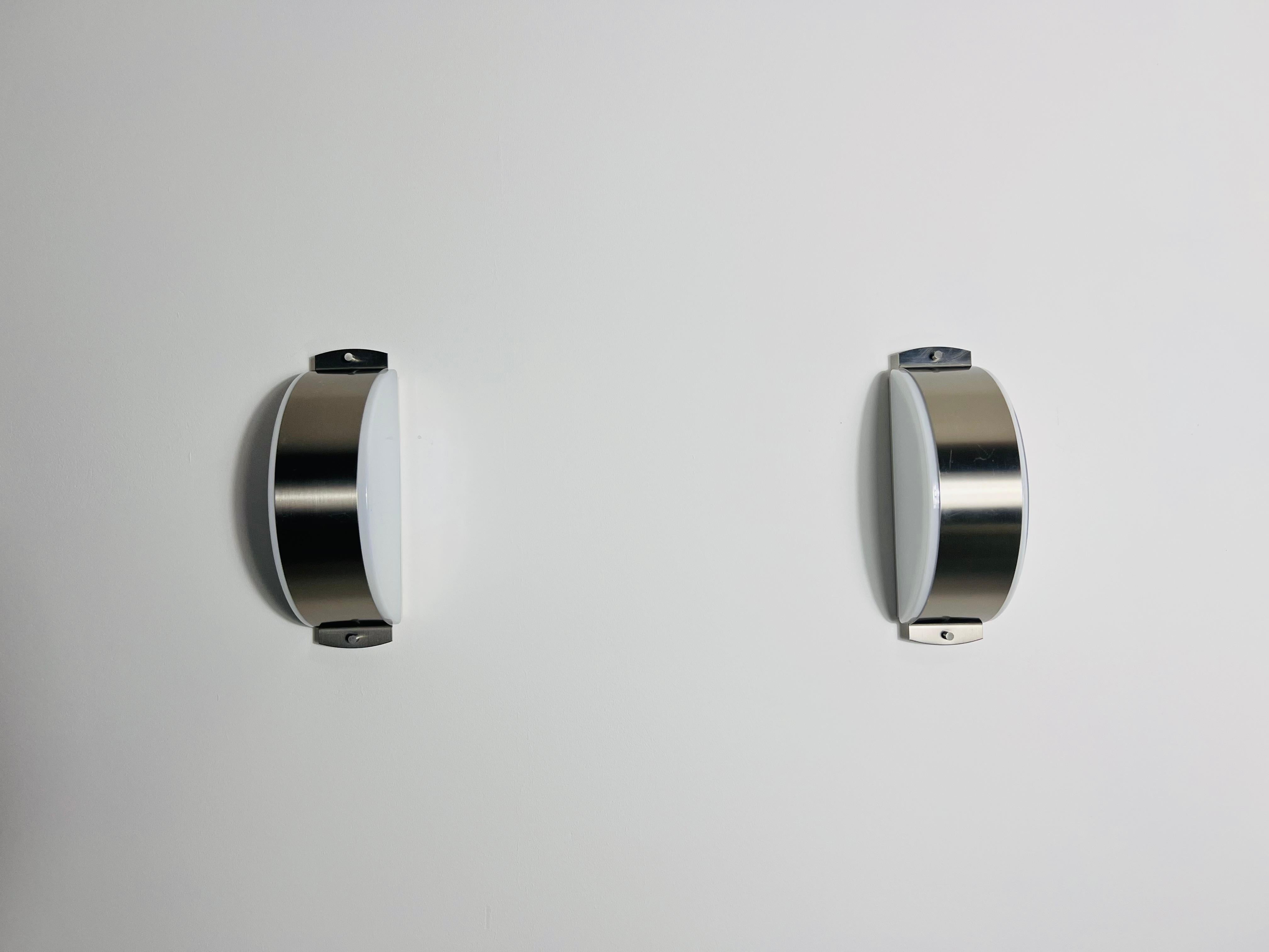 This pair of distinguished Limburg wall lamps, crafted in the 1960s, exemplifies the superior quality and precision of German workmanship. The lamp is elegantly designed with a chrome frame that encases a refined opal glass shade, which is securely