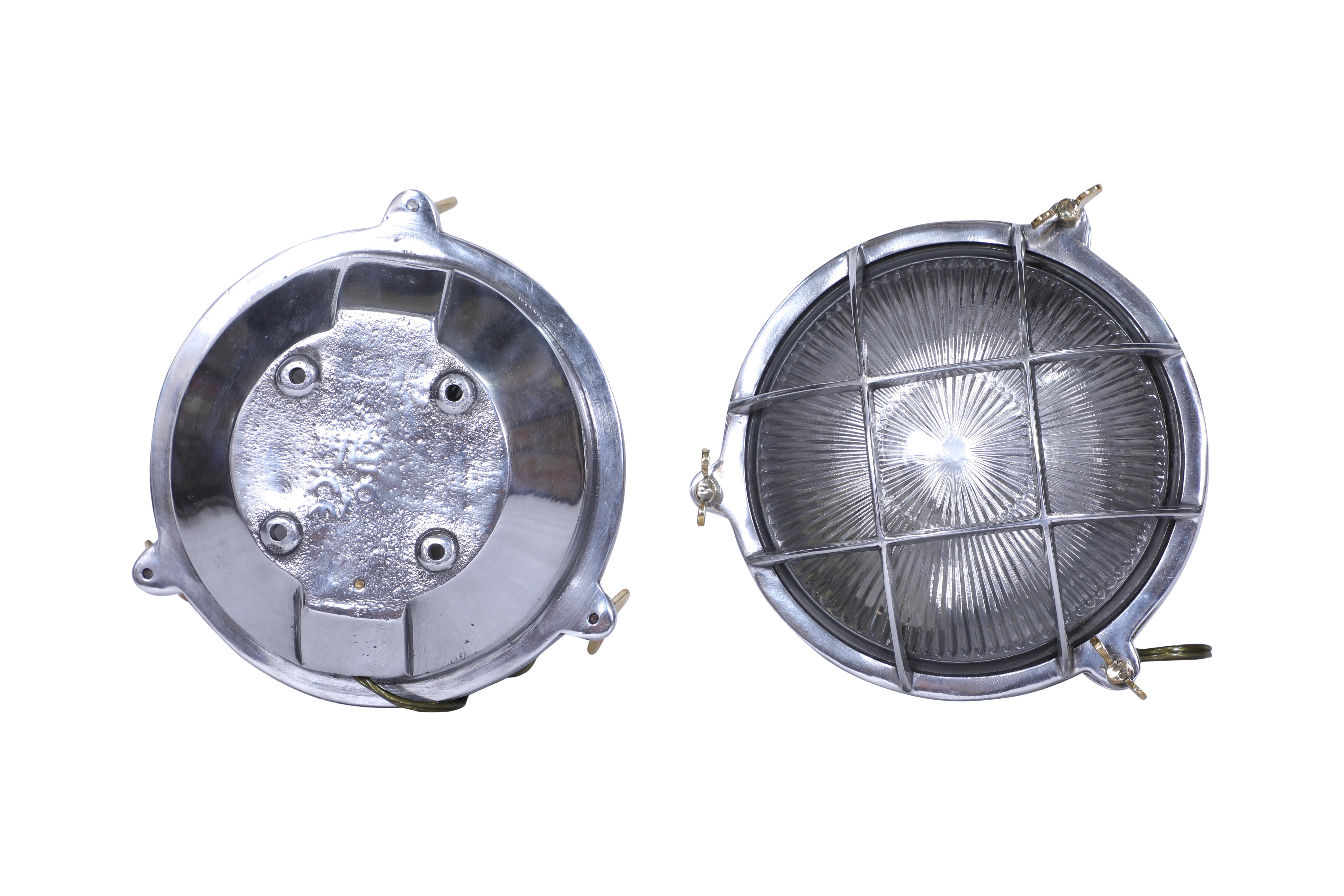 Pair of ship's chrome passageway lights with textured glass shade and chrome grid cage fronts.  Brass butterfly wing nuts to open.  Rewired for American use and takes a standard base light bulb.  Originally used in succession on a ship's passageway