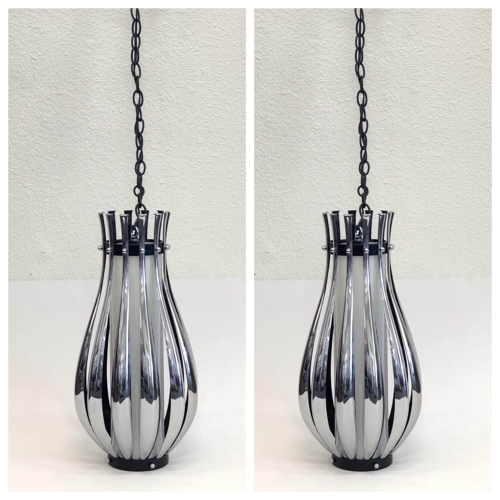 A glamorous pair of 1970s polish chrome and white glass pendant lamps by Sonneman. The lamps are chrome on the outside and black lacquer in the inside. A white glass cylinder covers the light bulb. The lamps can be used as hanging pendant lamps or
