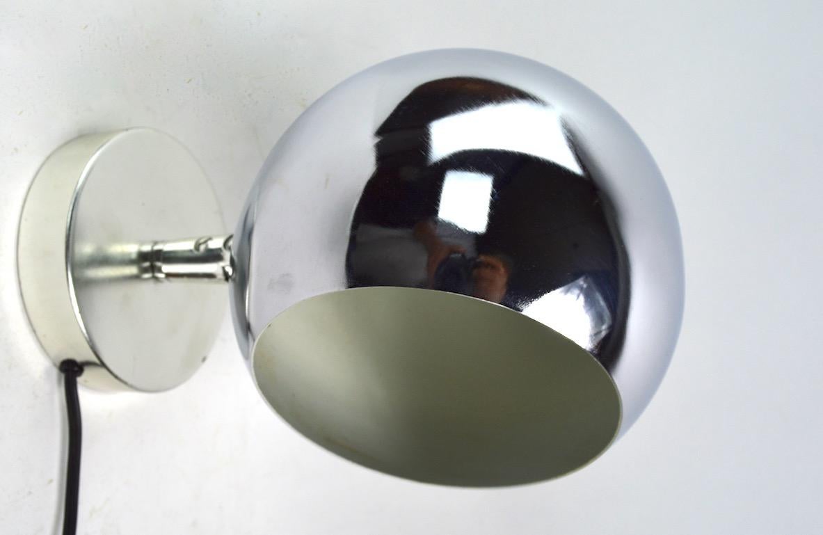 Pair of pin up sconces by Lightolier, each having an adjustable chrome ball hood shade (6 inch diameter). The sconces accept standard screwing incandescent bulbs, and are in good working condition. Diameter of backplate 4.5 inches. Priced and