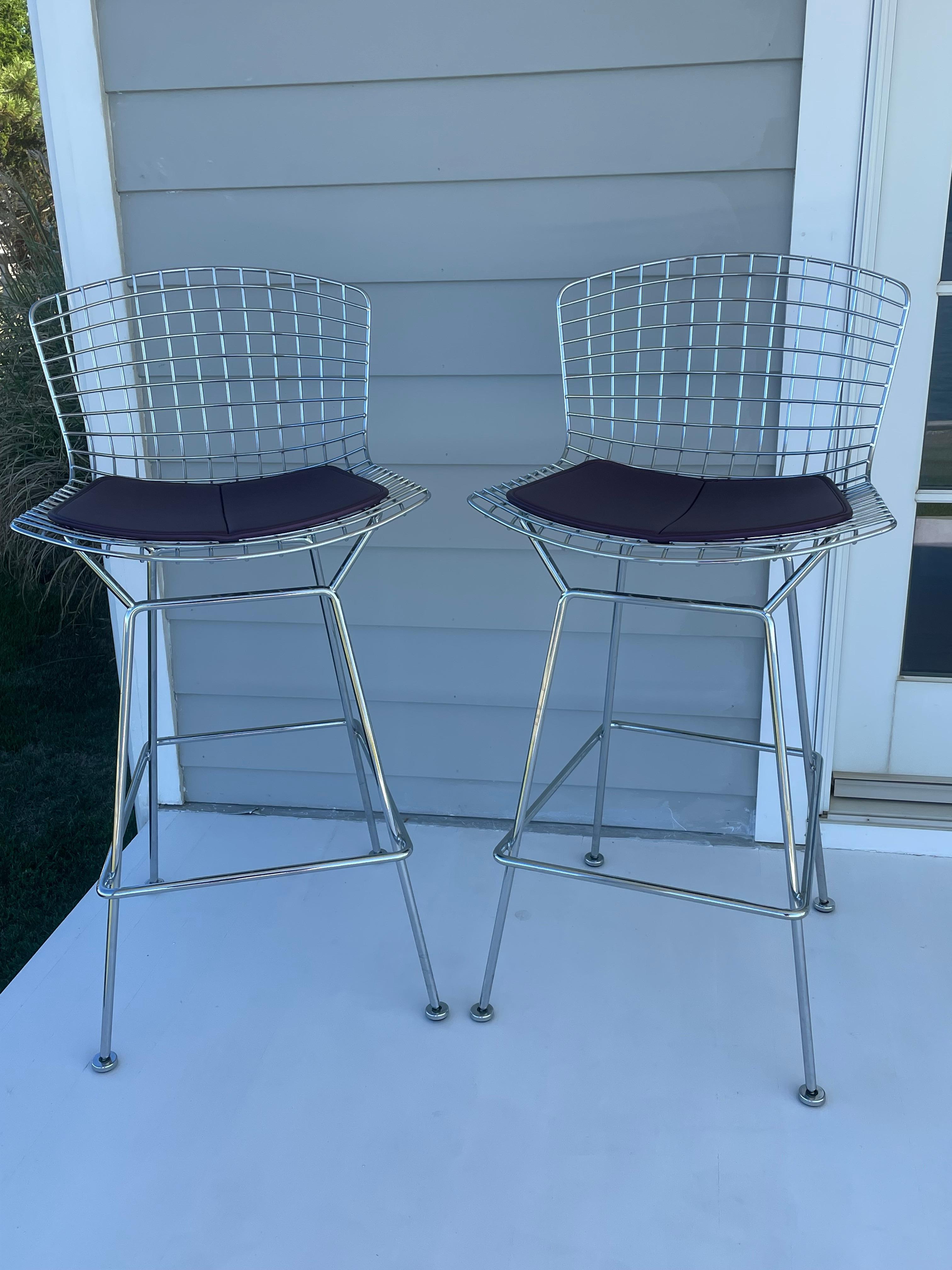 Beautiful iconic Harry Bertoia stools in a high chrome finish from Knoll with airy seats and welded rods. Originally designed in the 1950s with slight changes through the years. This pair is probably from the 2010s. Seat covers in a wine color and