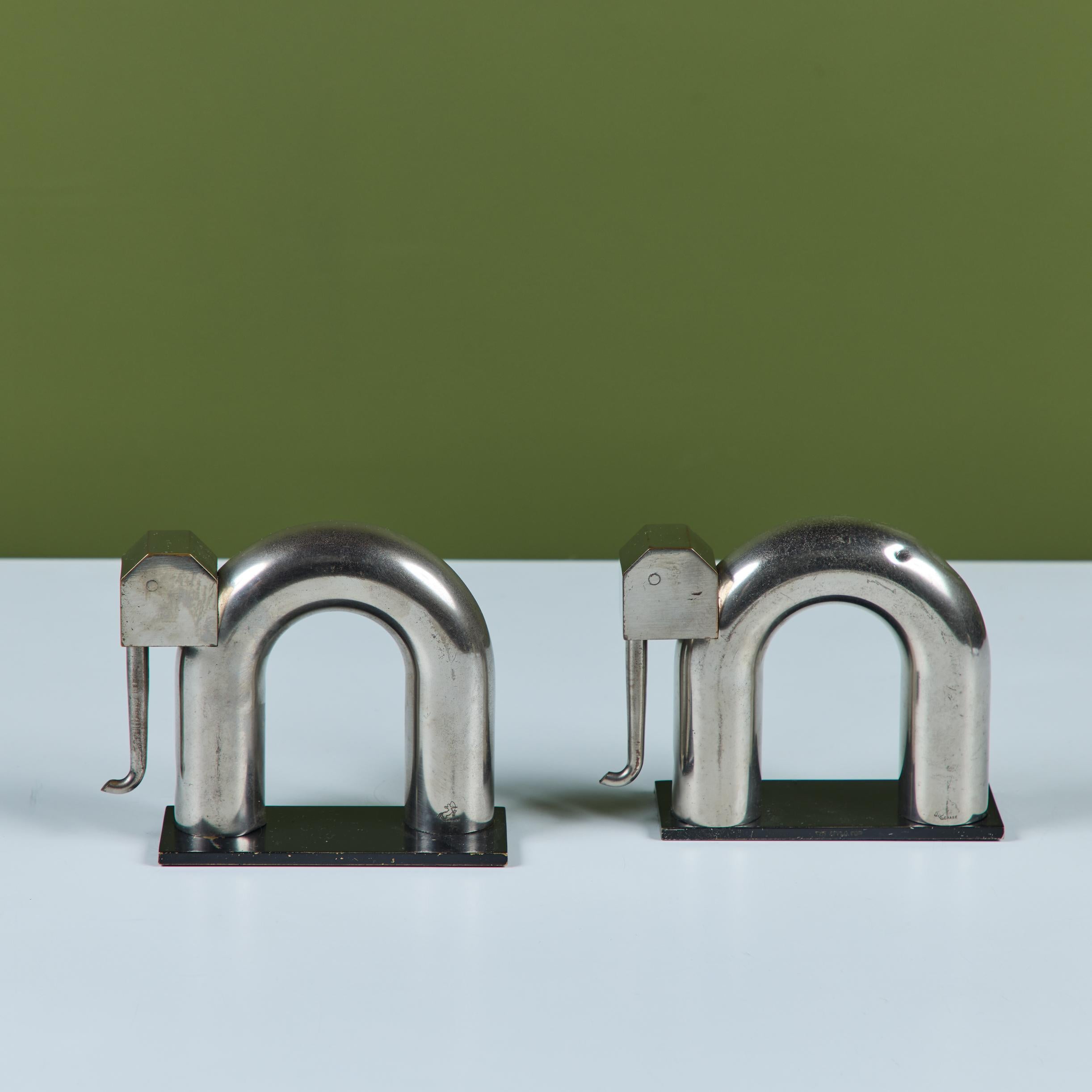 Coppia di fermalibri cromati di Walter Von Nessen per Chase, anni '30 circa, USA. La coppia di fermalibri presenta due elefanti in ottone cromato con corpi tubolari curvi e teste di forma geometrica con proboscidi delicate. Poggiano su una base