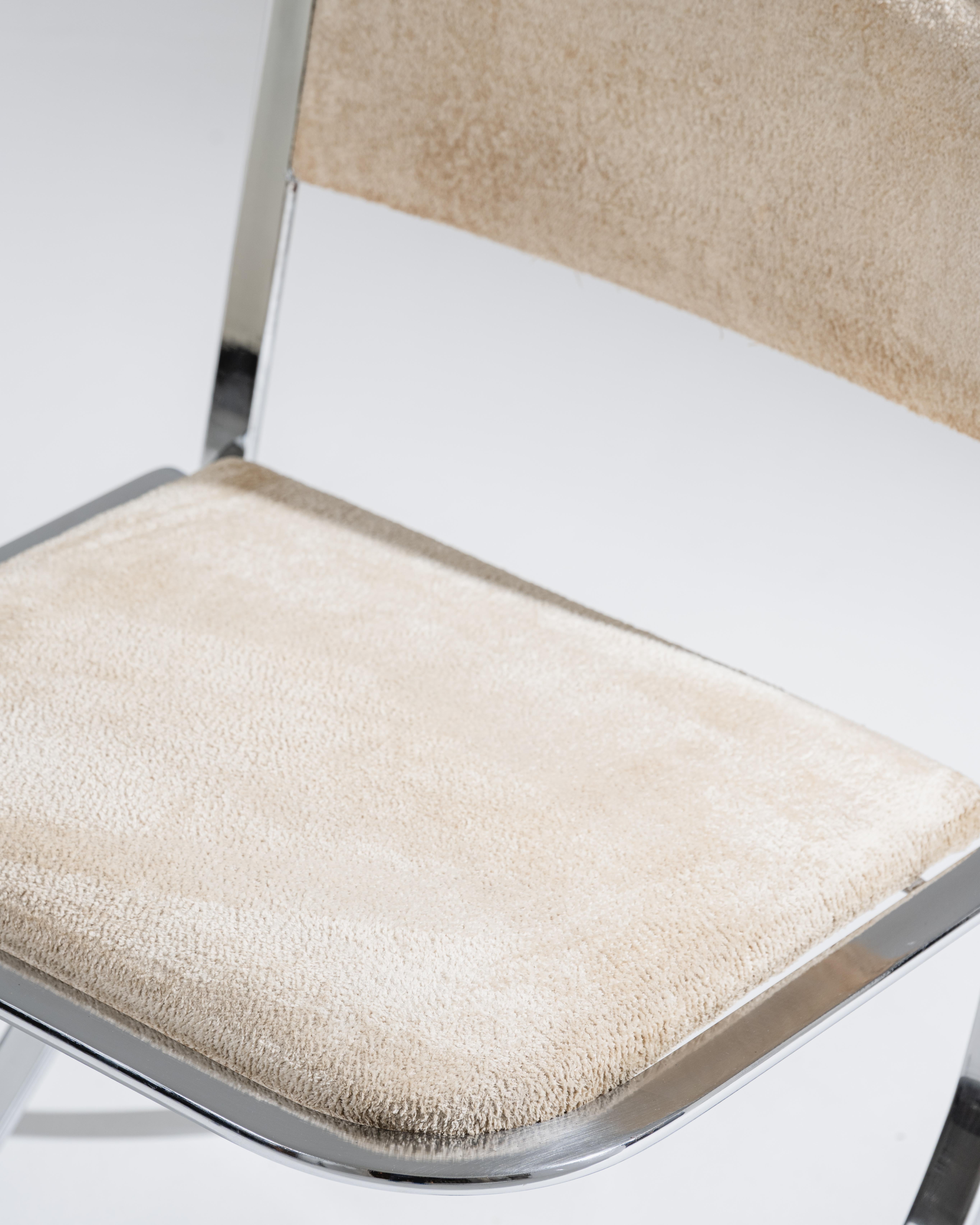 Coppia di sedie degli anni '70 che poggiano su una struttura tubolare in metallo cromato. La seduta e lo schienale sono rivestiti in velluto beige. La base presenta una struttura tubolare curva, caratteristica del design modernista dell'epoca.


In